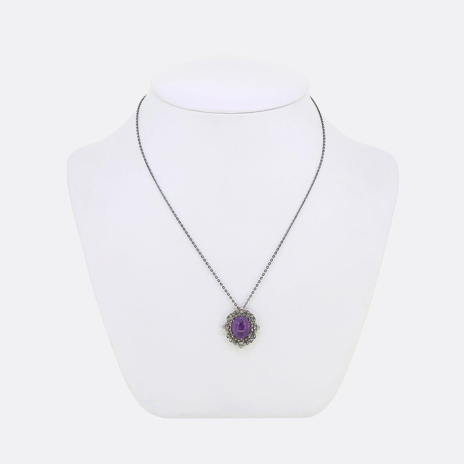 Here we have a charming amethyst and diamond necklace.

A sizeable oval shaped cabochon amethyst sits at the centre of an ornate mount and is accompanied by a vast array of rose cut diamonds. This foliated design is set upon a yellow gold backing