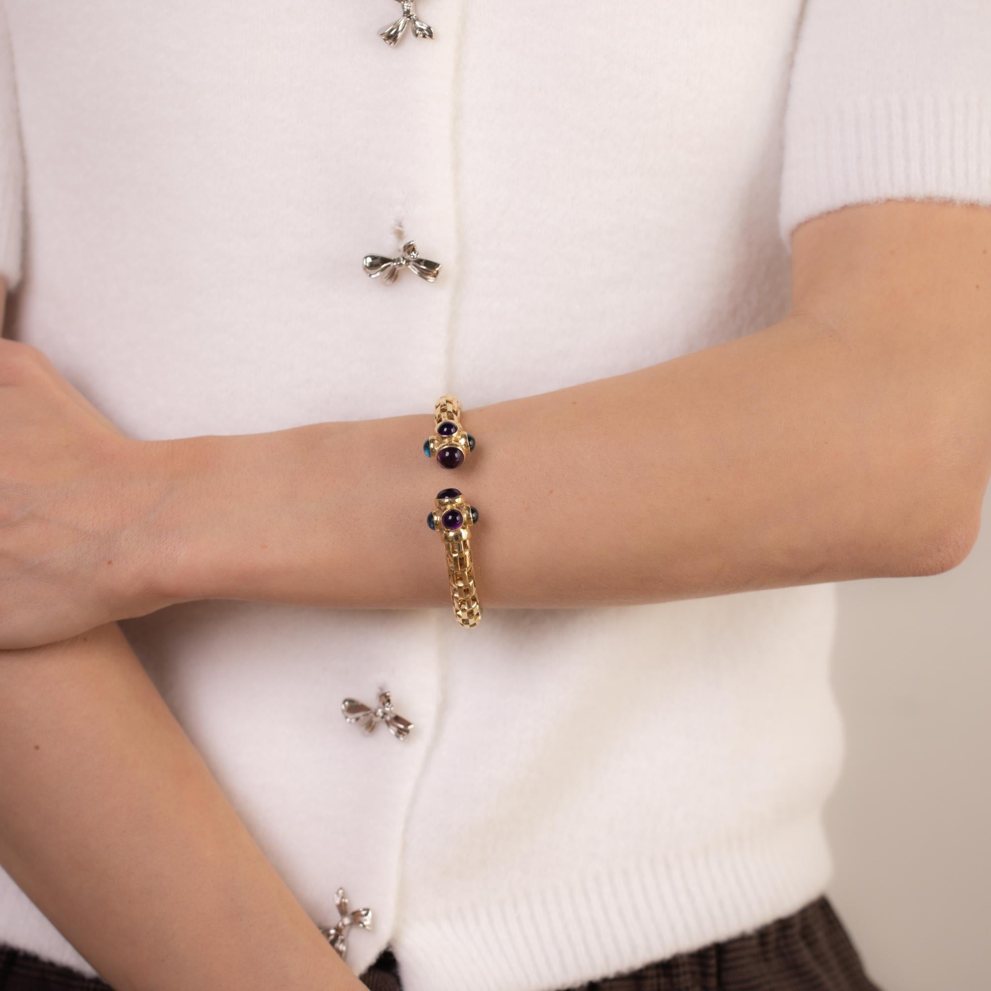 Dieser Armreif aus 14-karätigem Gelbgold besteht aus 10 lebhaften Amethysten und blauen Topasen im Cabochon-Schliff, die in einem kühnen und doch raffinierten Design gefasst sind. Ein auffälliges Stück mit reichem Farbkontrast und zeitloser