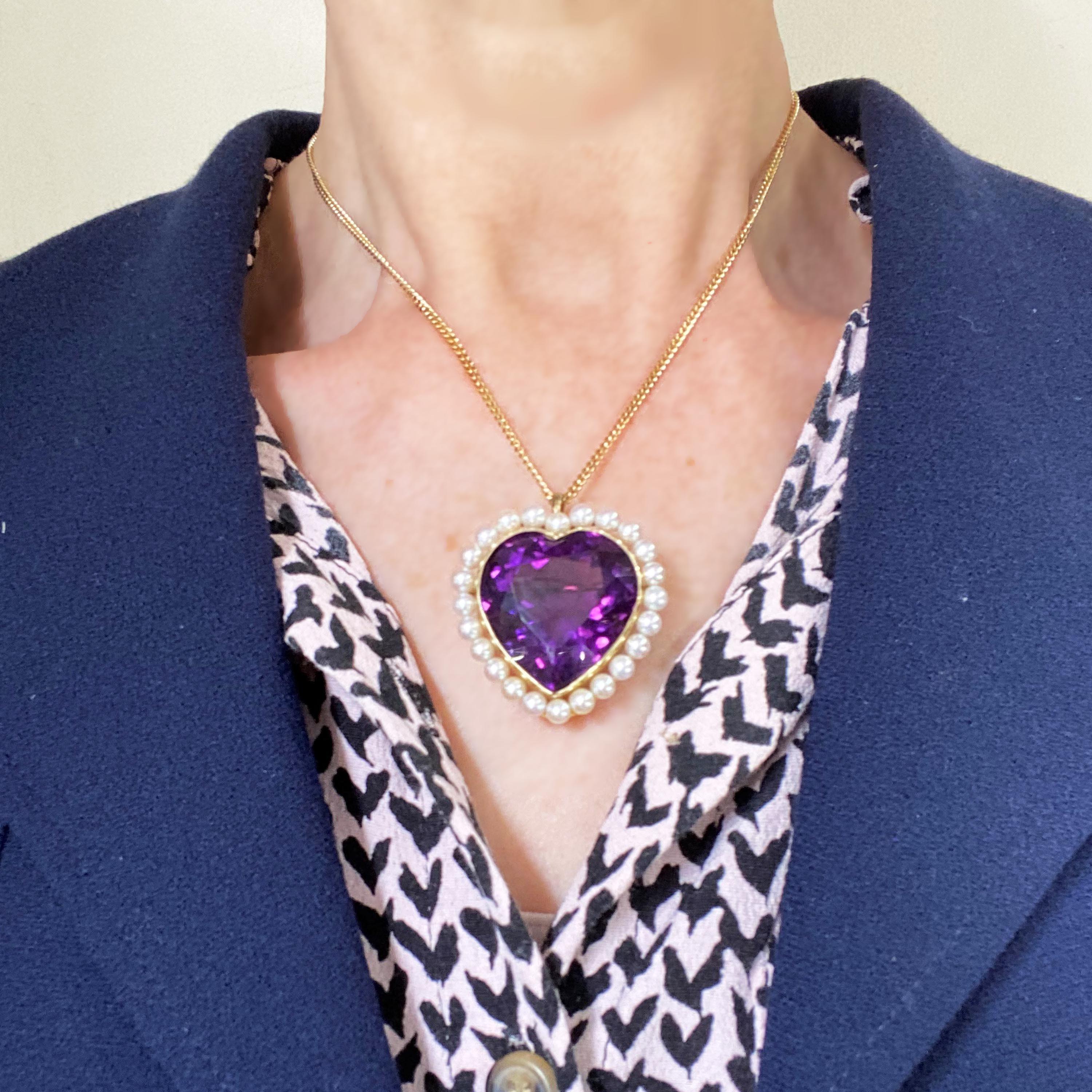 A vintage amethyst and cultured pearl heart brooch-cum-pendant, set with a large, faceted, heart shaped amethyst, in a millegrain edged rub over setting, surrounded by 24 cultured pearls, mounted in 14ct gold, with a pin with a safety hook, with a