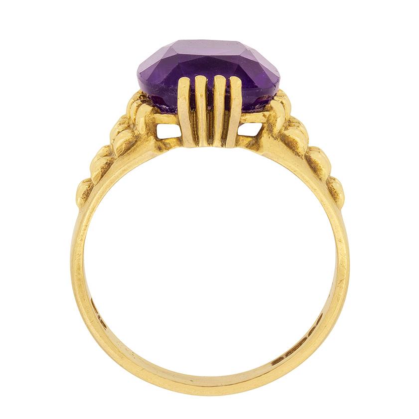 Dating to the 1960s, this dress ring features a 5.00 carat purple amethyst. The ring has been handmade within 9 carat gold and the centre stone, which is a cushion cut, has been claw set. The detail adds character and the linked effect on the