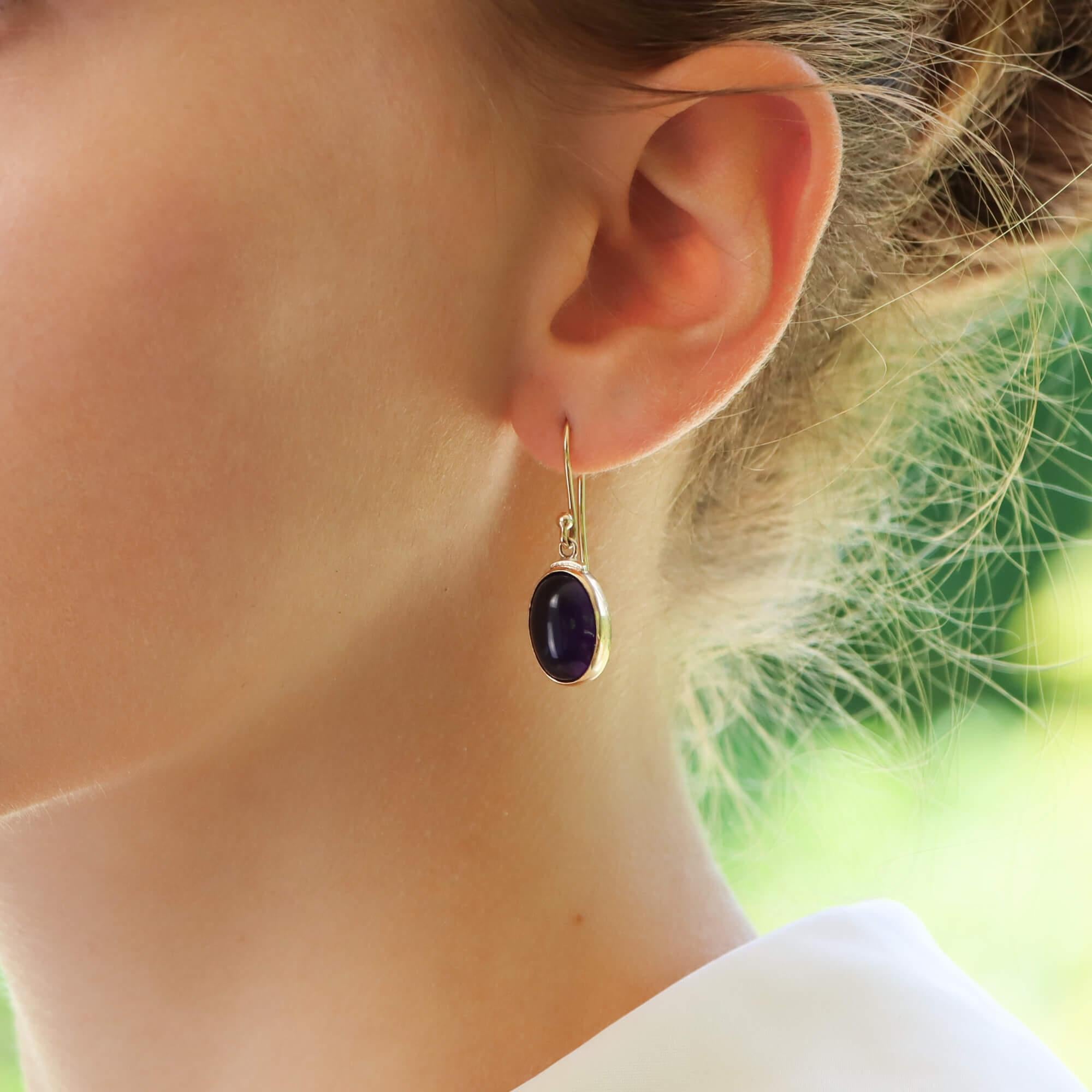  A beautiful pair of amethyst drop earrings set in 9k yellow gold.

Each earring solely features an elegant cabochon oval amethyst stone which is securely rub over set. The amethysts have a fantastic colouring and lustre to them which make them