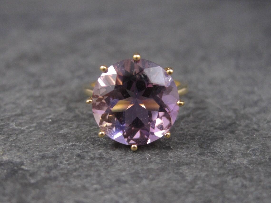 This stunning ring is 10k yellow gold. It would make a stunning alternative engagement ring.

It features a huge, natural, round cut, 6.4 carat amethyst stone.

The face of this ring measures 1/2 inch with a rise of 10mm off the finger.
It is a size