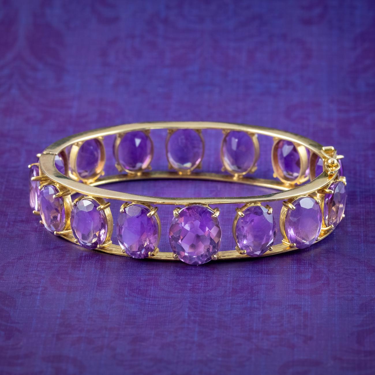 A regal vintage eternity bangle from the late 20th Century adorned with fifteen glorious oval cut amethysts chasing around the entire circumference. They have a deep, purple hue and weigh approx. 4ct each with a larger 6ct stone at the front,