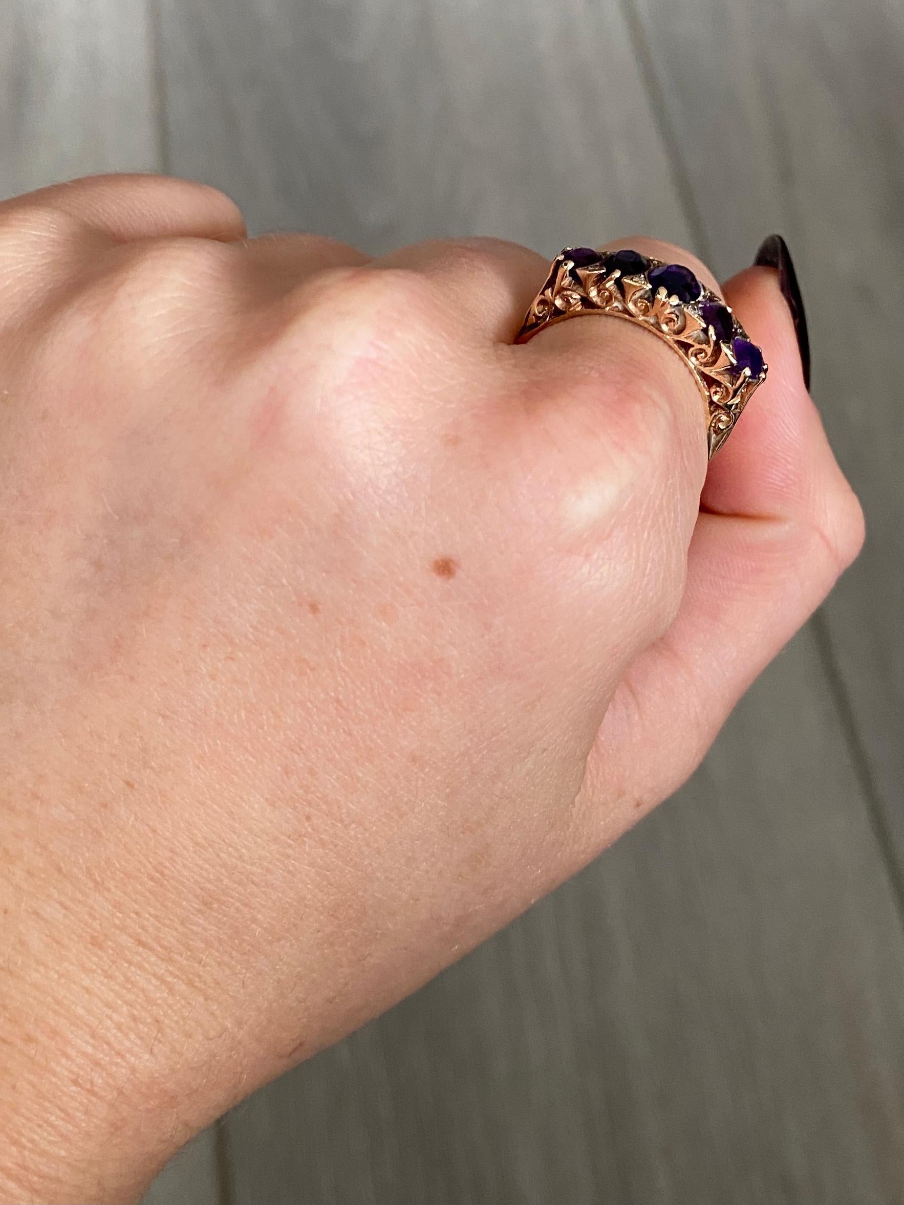 Dieser Ring enthält nicht nur fünf leuchtende und funkelnde Amethyste, sondern auch Diamantenspitzen. Alle Steine sind in Gold gefasst und haben eine verzierte Galerie. Sogar die Schultern dieses Rings sind mit dem Wirbeldetail versehen.
