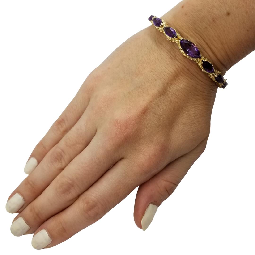 14 Karat Yellow Gold Bangle Featuring 7 Graduated Marquise Cut Amethysts Totaling Approximately 5 Carats. Hinged Clasp with Granular Textured Details. Finished Weight is 18.3 grams. 
