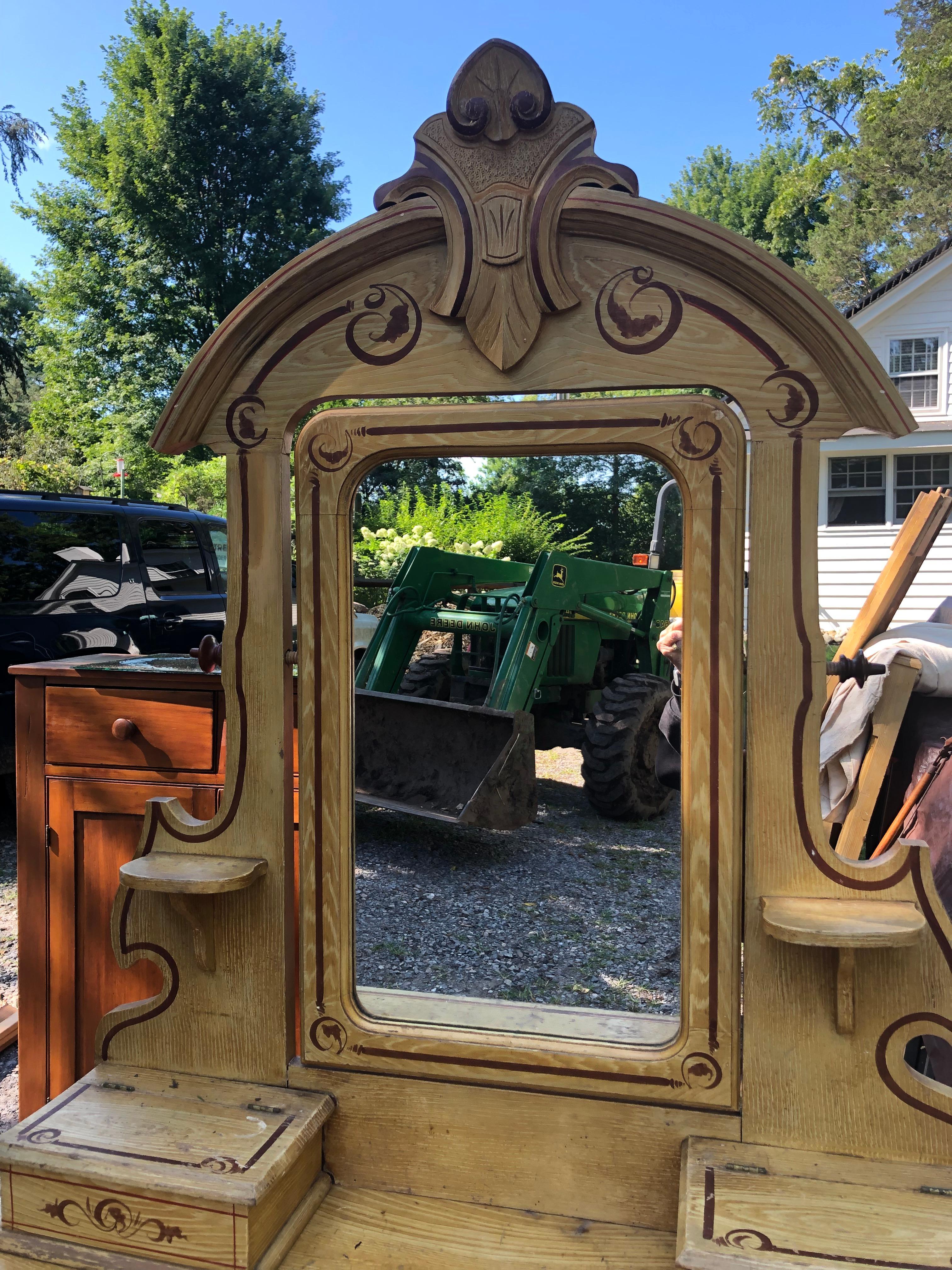 Charming Amish made chest of drawers with matching attachable mirror.  Comes in two pieces.  The wood is in distressed condition and the hardware shows wear, but the hand painted decoration, two boxes that open on top, and carved wood cornice give