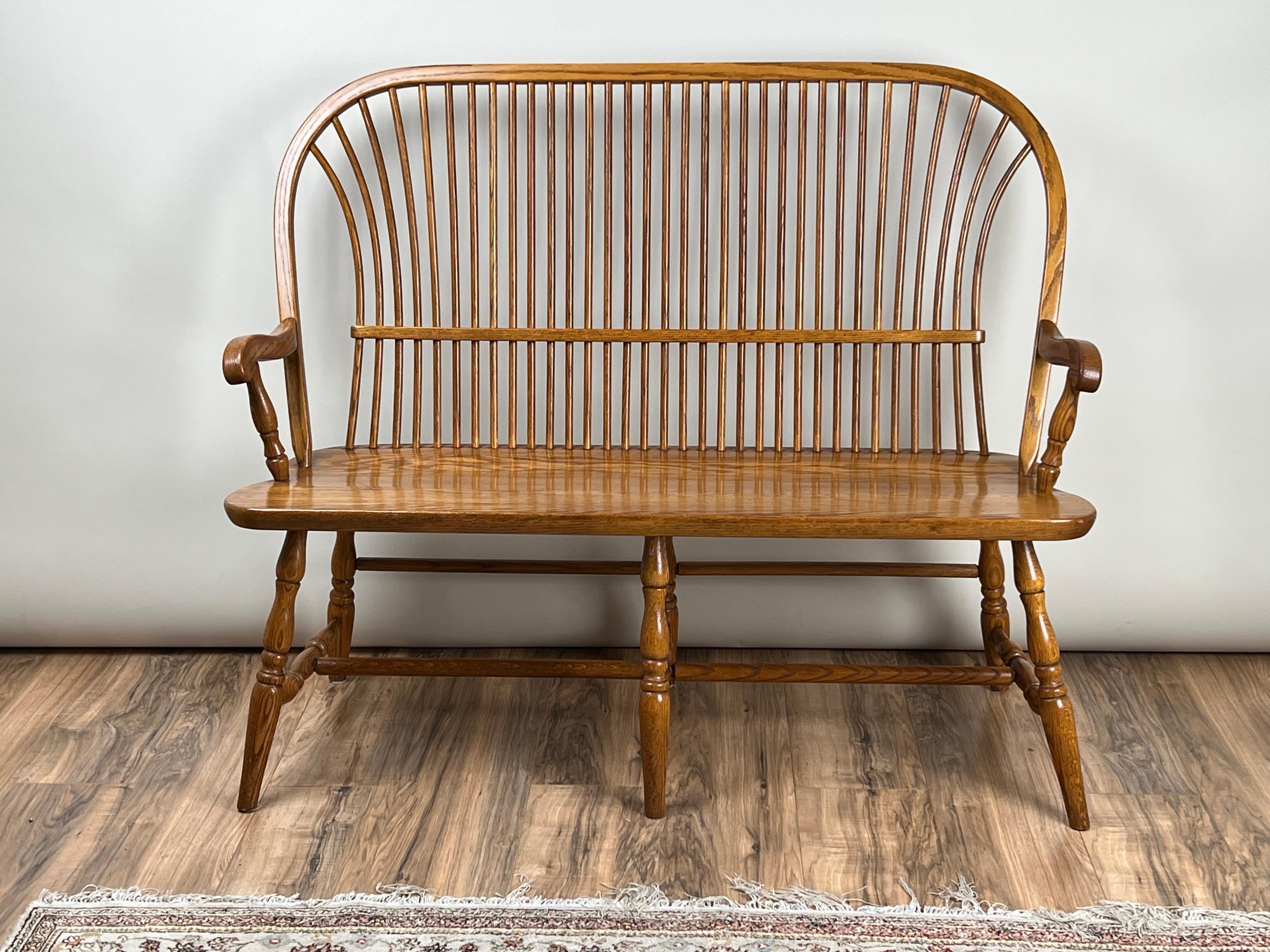 This vintage Amish oak Windsor bench is a beautiful example of traditional American craftsmanship. With its tall spindle back and gently curved crest rail, the piece reflects the enduring appeal of the Windsor form — a style that has been beloved