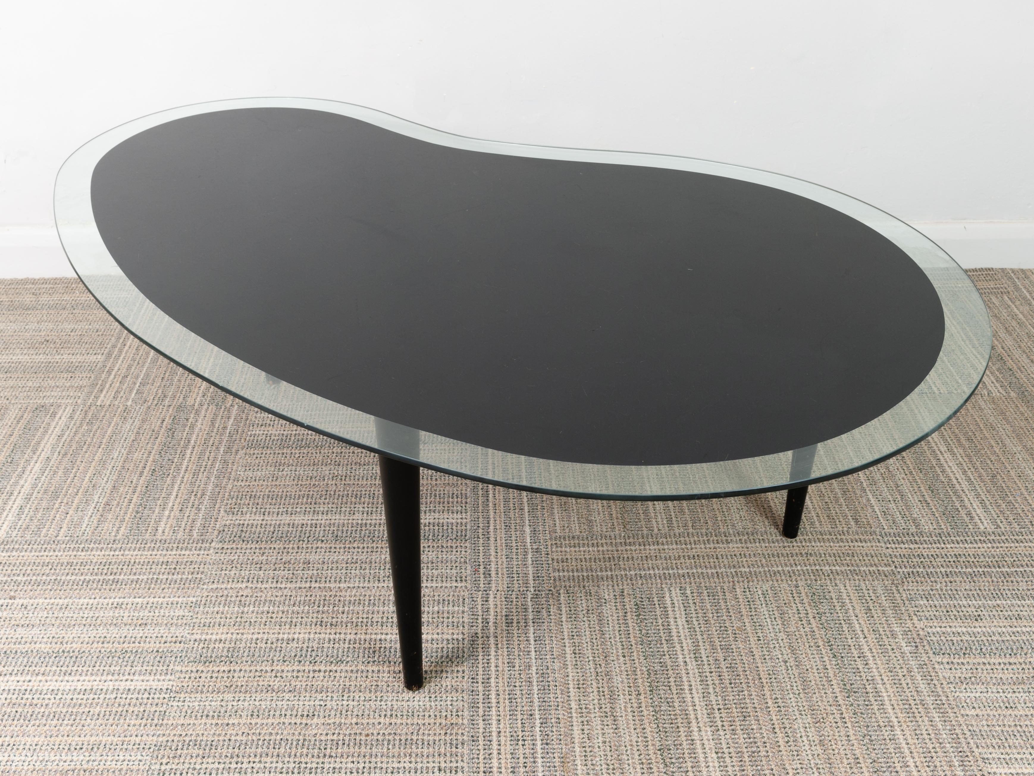 Vintage 1960s Amoeba or Kidney shaped coffee table with a black inner glass design which follows the shape of the table with a clear outside edge. The table has three removable ebonised wooded legs that unscrew for storage. There are scratches to