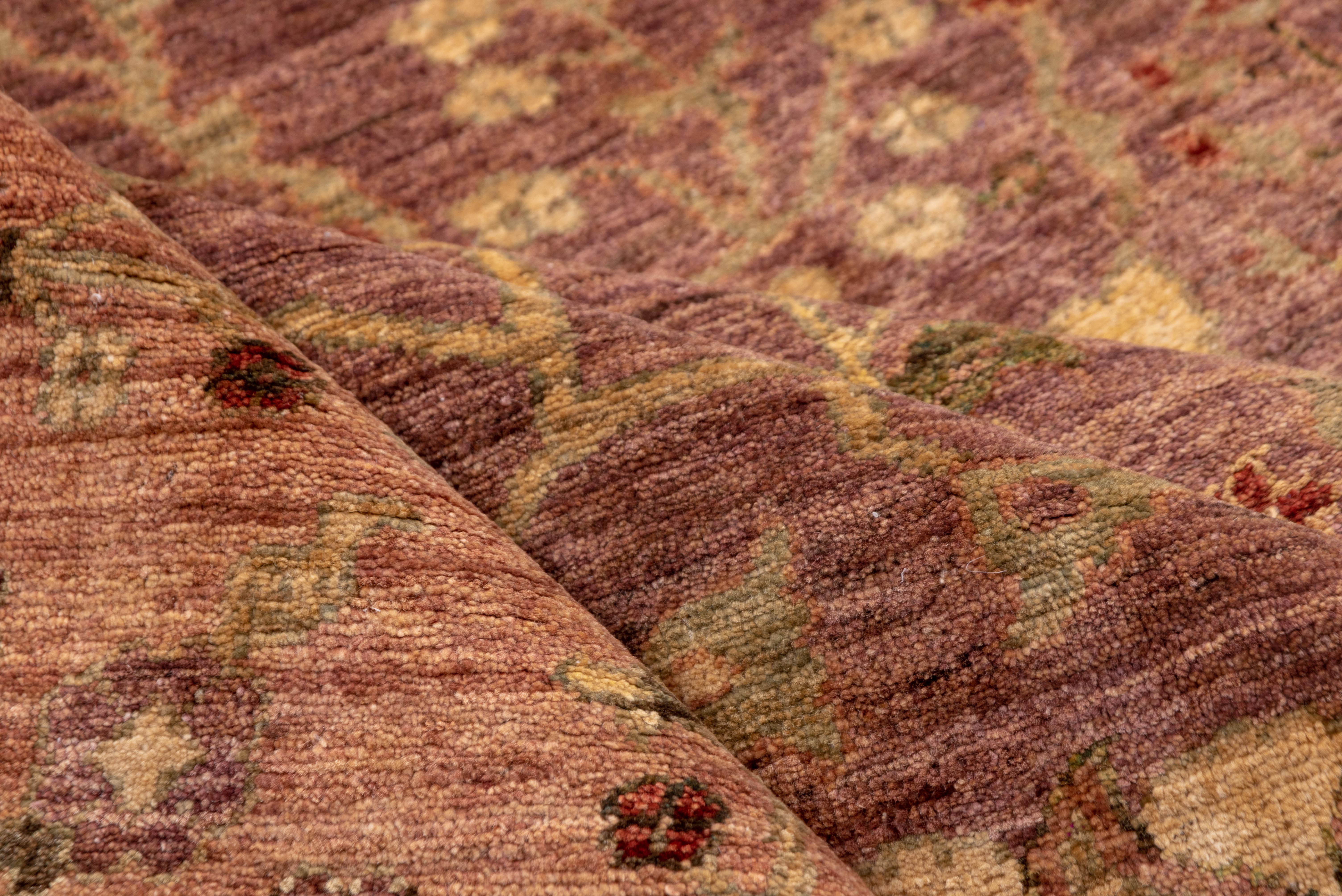 Dieser Amritzar-Teppich im Vintage-Stil bietet mit seinem zartrosa-pflaumenfarbenen Feld, das durch eine Reihe von elfenbeinfarbenen und blassgoldenen Blumenmotiven, die in einer symmetrischen, vom Lebensbaum inspirierten Komposition angeordnet