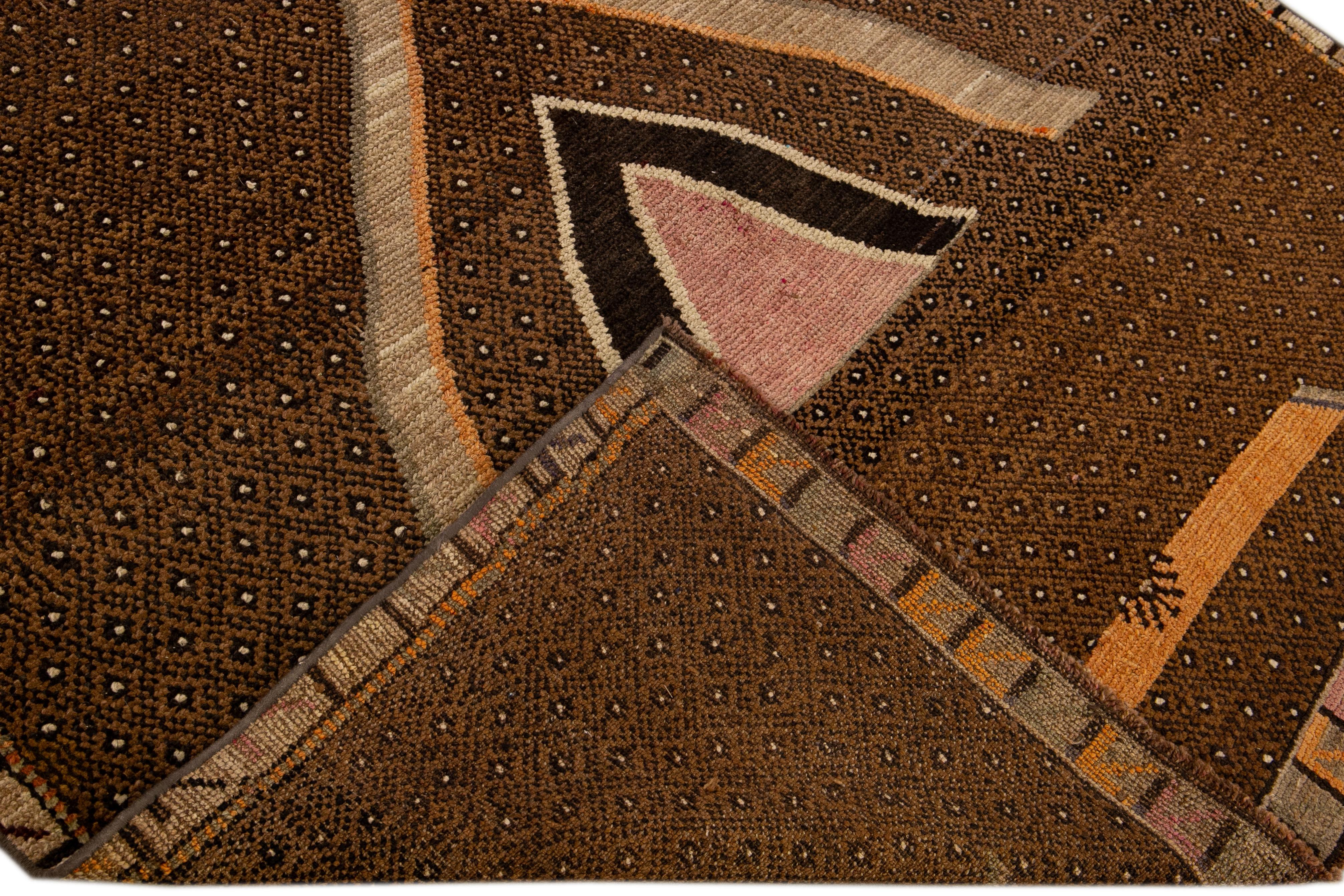 Beautiful vintage Anatolian Kars hand-knotted wool rug with a brown field. This piece is orange, pink, and gray accents in a geometric design. 

This rug measures 5'6