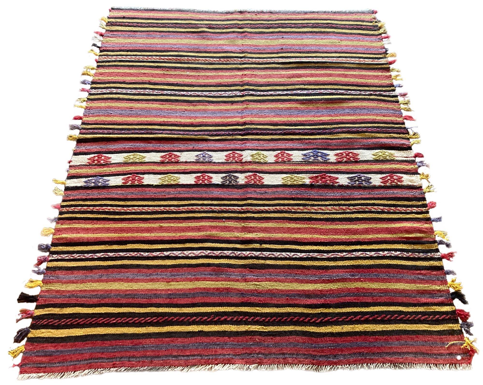 A lovely vintage kilim, handwoven in central Turkey circa 1960 featuring a multicoloured banded design in reds, greys and golds. Note the funky tassels along each side!
Size: 1.77m x 1.38m (5ft 9in x 4ft 6in)
This kilim is in good condition with