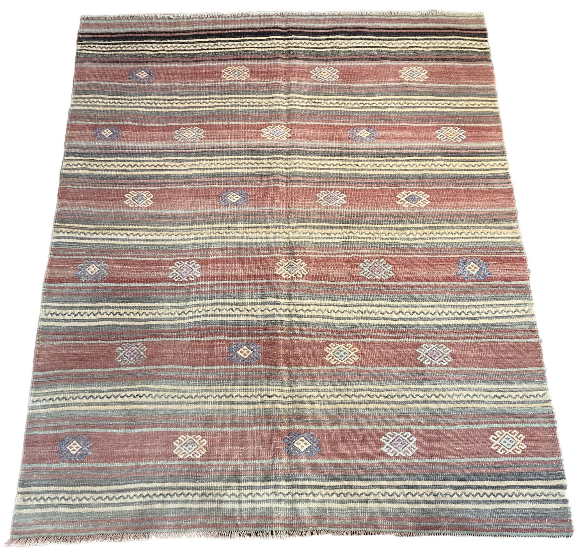 A beautiful vintage kilim, handwoven in central Turkey circa 1960 featuring a traditional multicoloured banded design in soft pinks and greys.
Size: 1.90m x 1.53m (6ft 3in x 5ft)
This kilim is in good condition with light, age related wear. The