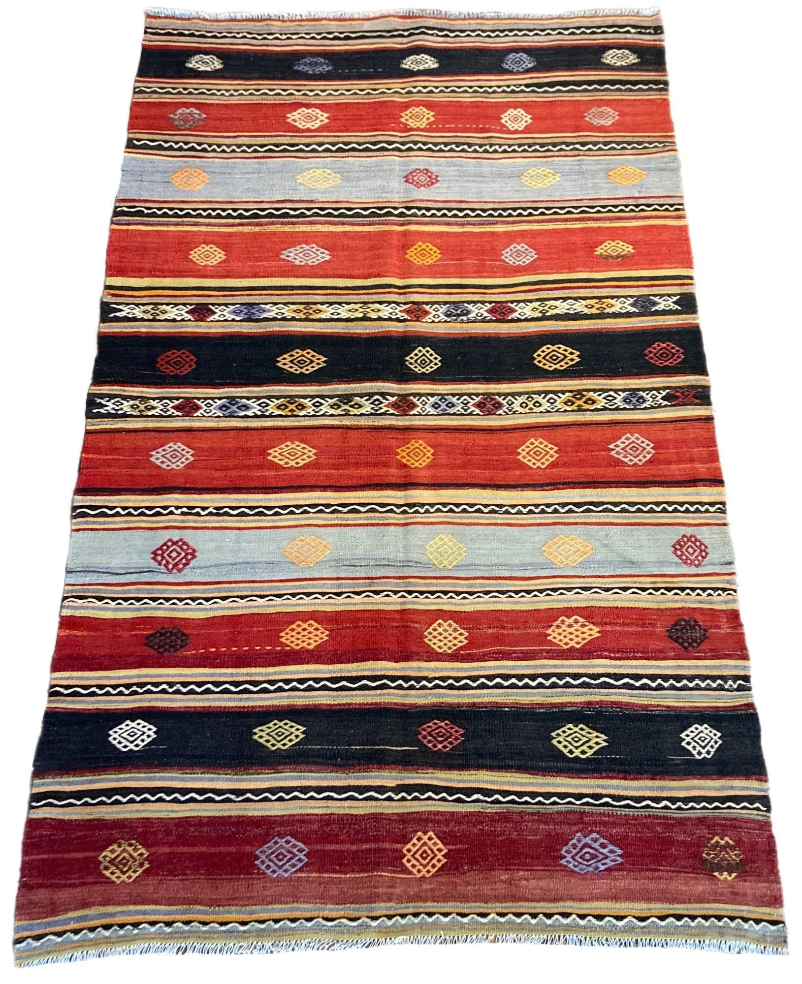 A beautiful vintage kilim, handwoven in central Turkey circa 1960 featuring a multicoloured banded design in blues, reds, dark greys and golds.
Size: 2.17m x 1.32m (7ft 2in x 4ft 4in)
This kilim is in good condition with light, age related wear.