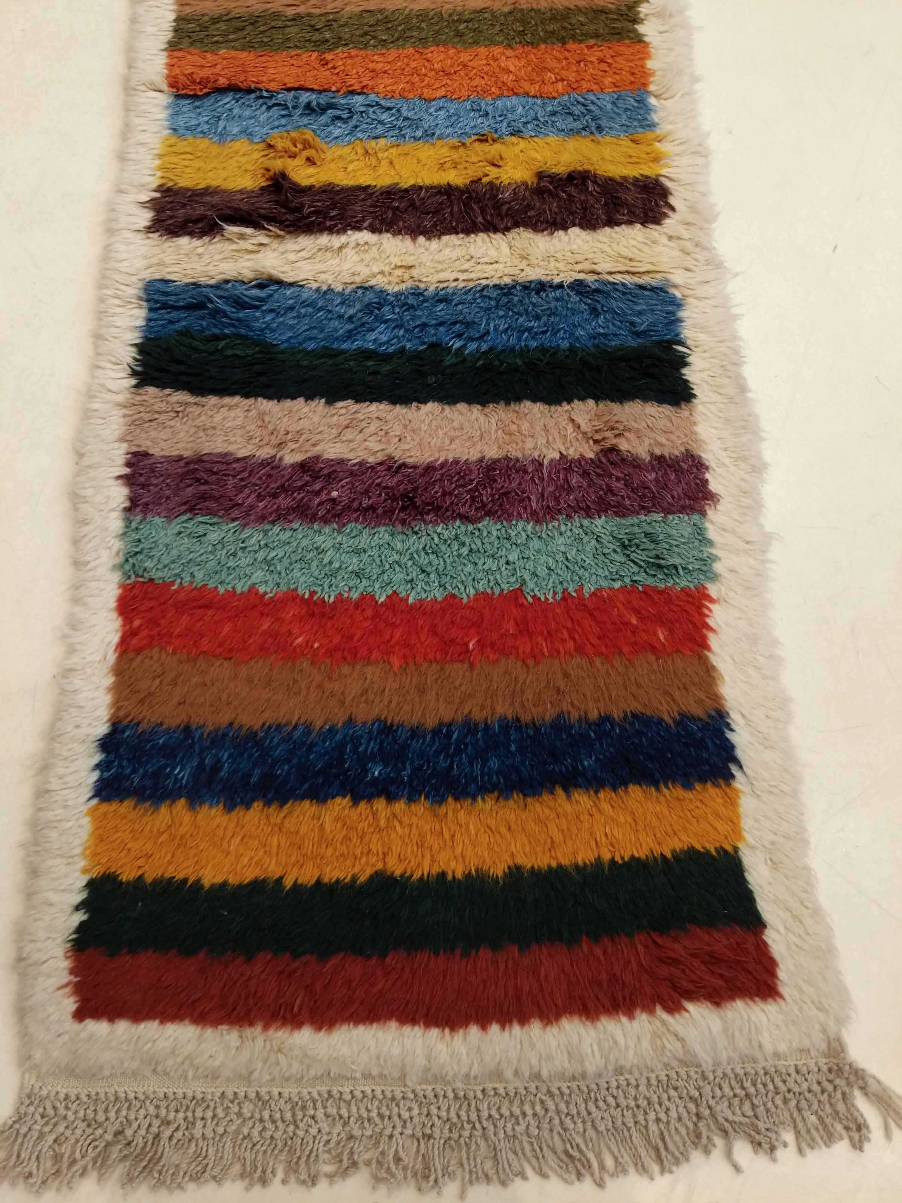 A truly spectacular runner distinguished by a plethora of colours arranged as horizontal stripes. Tulu rugs represent one of the earliest forms of nomadic pile weaving, typically knotted with a medium-high pile as they were meant as bedding rugs for