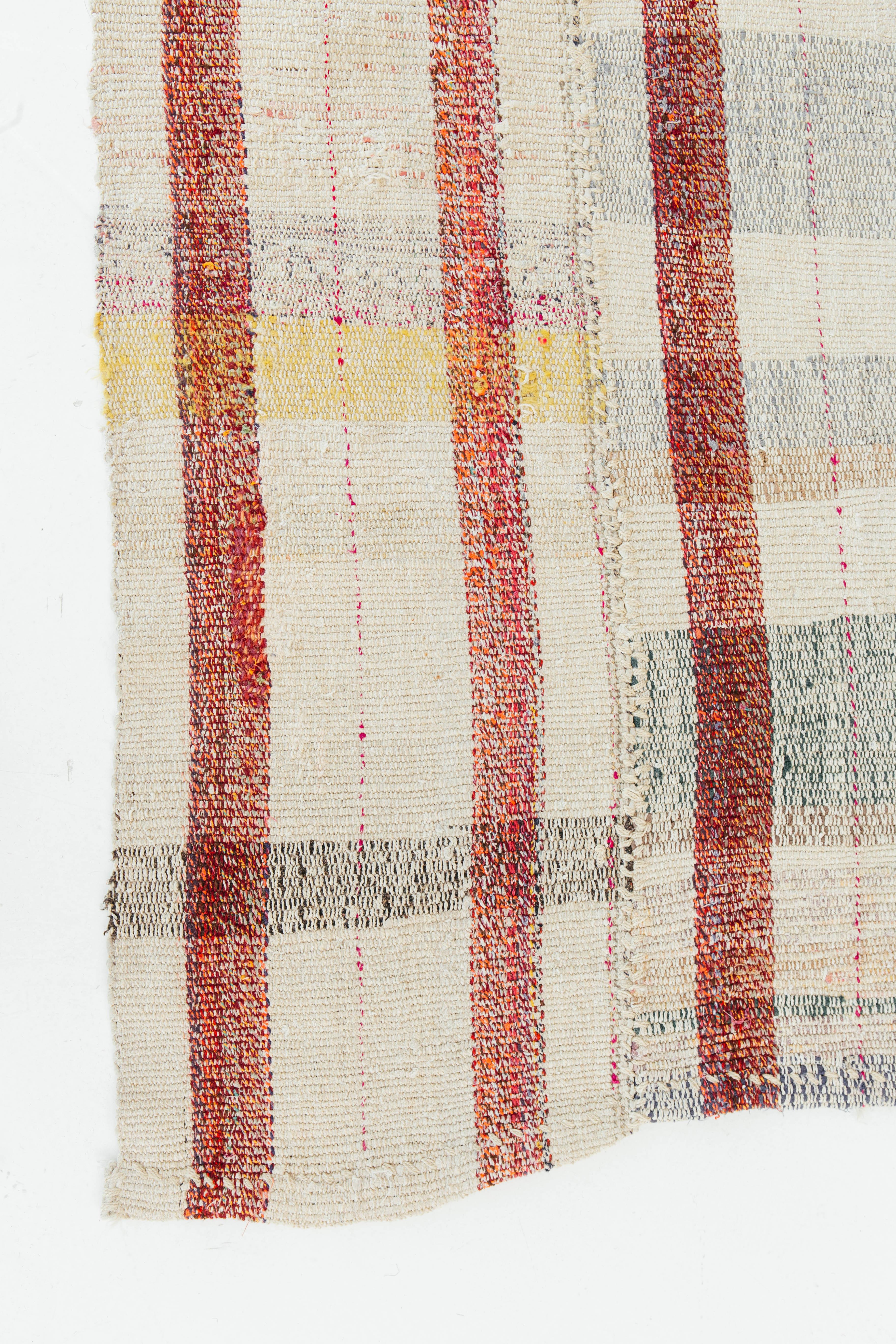 A unique vintage Anatolian Turkish rug that weaves together beautiful colors to create an irregular plaid pattern. Red vertical stripes bring a bold and playful essence meanwhile sporadic colors of yellow, green, and blue peak through. Vintage