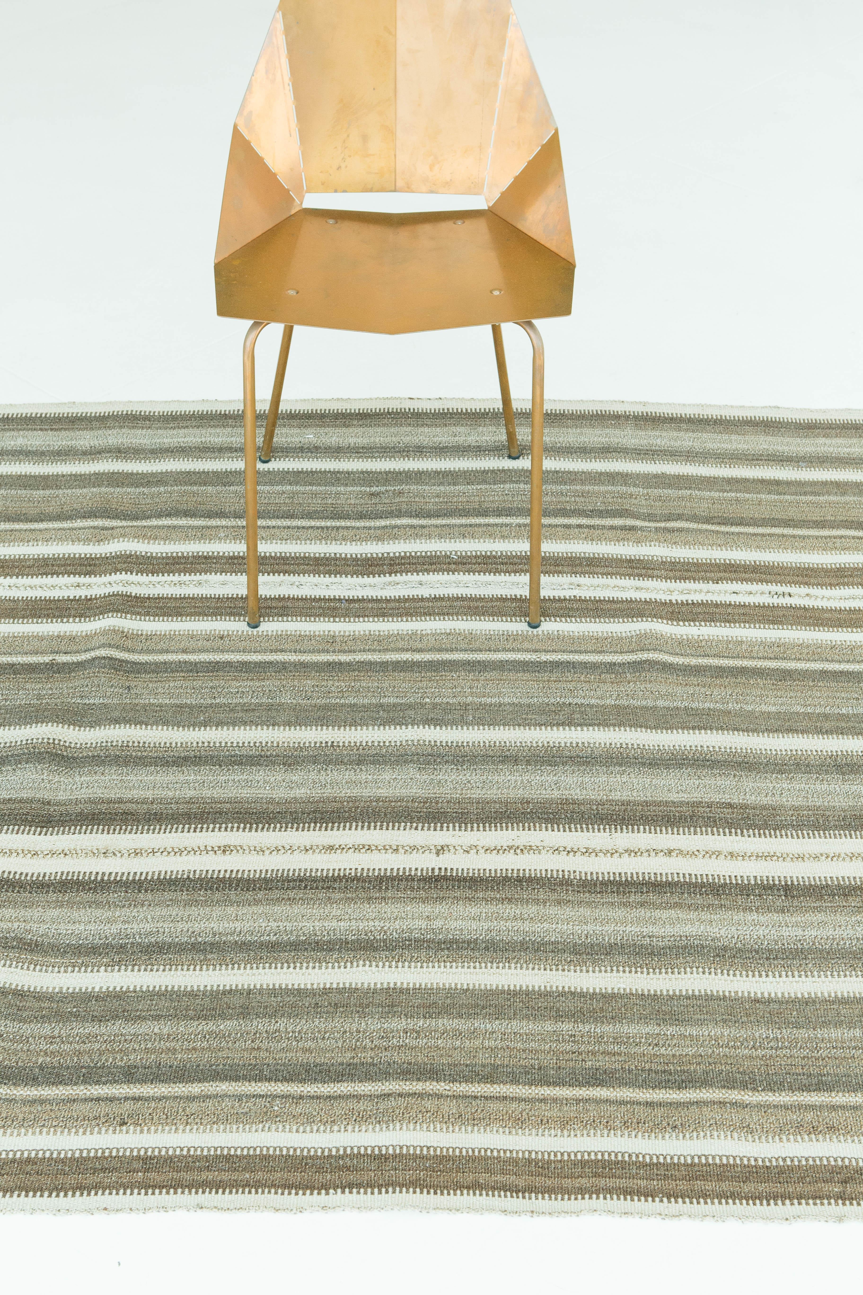 A vintage Anatolian Turkish flat-weave Kilim. This piece is the epitome of natural elegance. Its brown and ivory colors and toothing detailing alongside the rug's stripe pattern creates a simple yet interesting design. This flat-weave's interesting