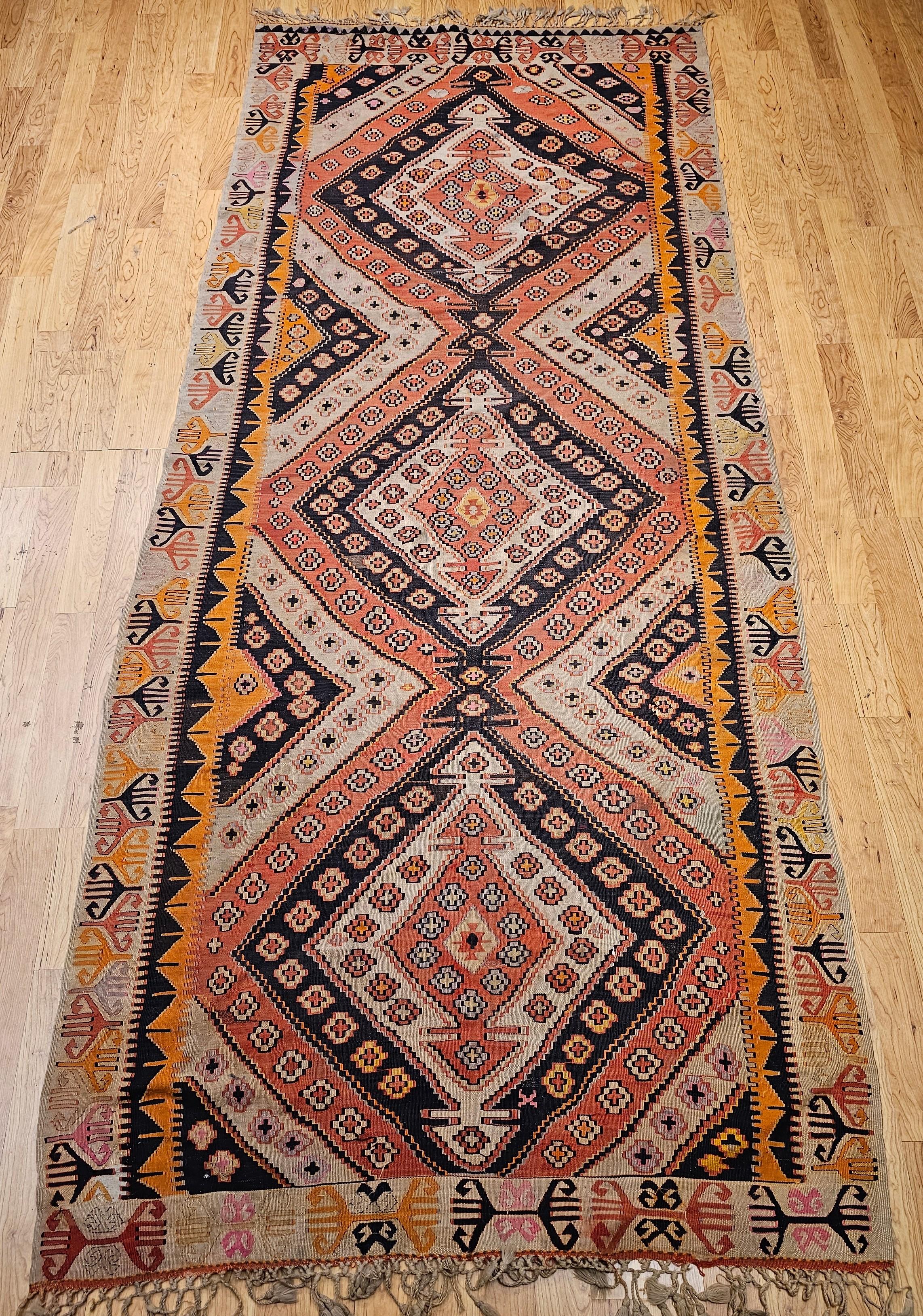 Vintage Turkish kilim is considered a gallery/corridor rug or a wide runner.  The Turkish kilim is a  flat woven rug from the early 1900s.  It has beautiful colors including pale brick, tan, navy and yellow.  The design contains three connected