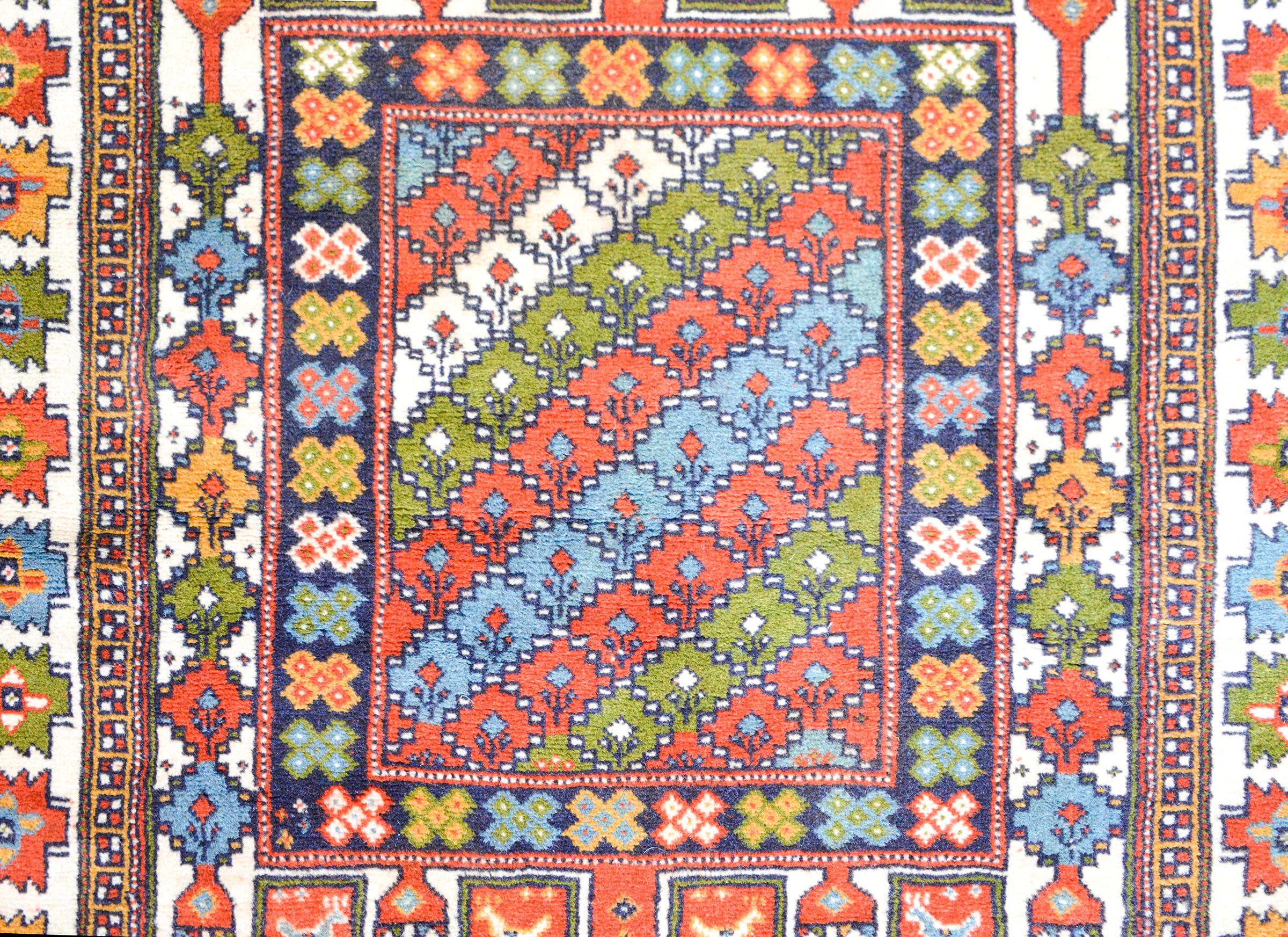 A stirking vintage Anatolian Turkish rug with a richly colored pattern of stylized flowers, chickens, and trees-of-life, all woven in bright corals, greens, golds, and blues, and surrounded by a border with more stylized flowers.