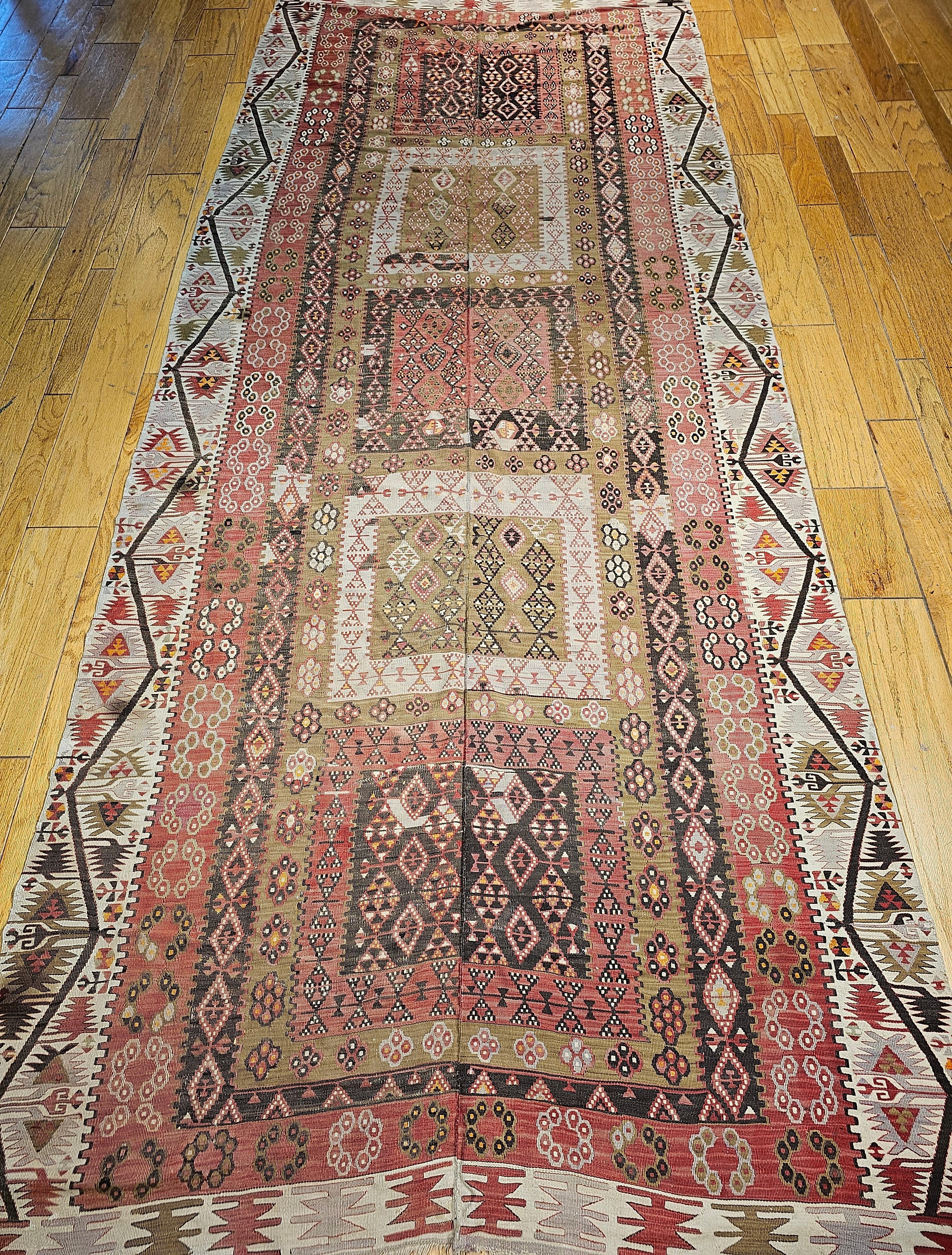 Vintage Turkish gallery rug or a wide runner flat woven kilim from the early 1900s.  The kilim has beautiful soft colors including pale brick red in the field which is formed by 5 large rectangular medallions in a column in different colors and