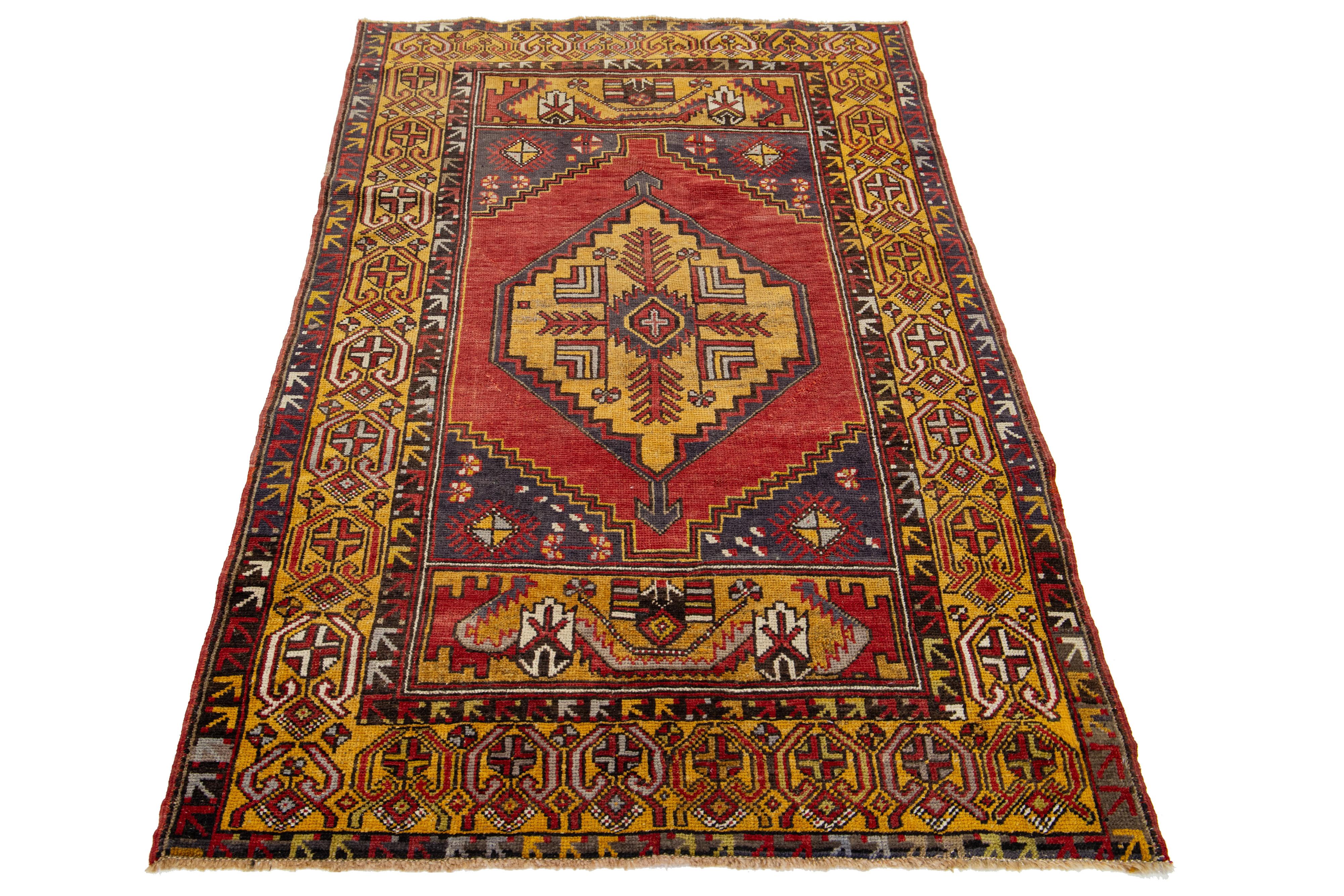 A vintage Anatolian rug, hand-knotted, featuring a geometric design displayed on a red field, bordered by yellow sections, and adorned with blue hues.

This rug measures 3'8