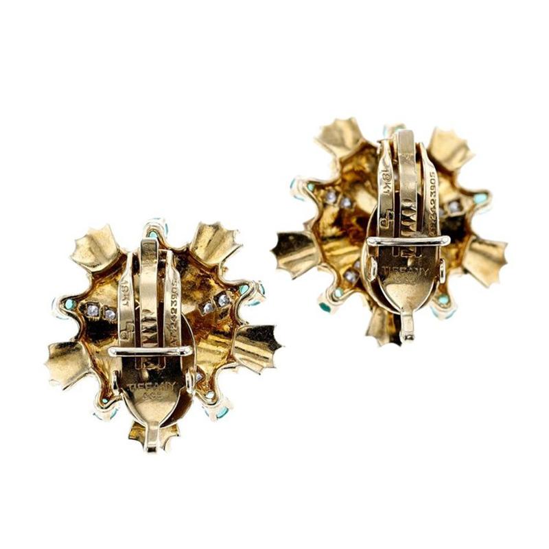 A chic pair of emerald and diamond vintage and retro earrings by Tiffany & Co. The earrings are meticulously crafted in a starburst design pattern and set with round brilliant-cut emeralds and diamonds in 18k yellow gold. The earrings are signed