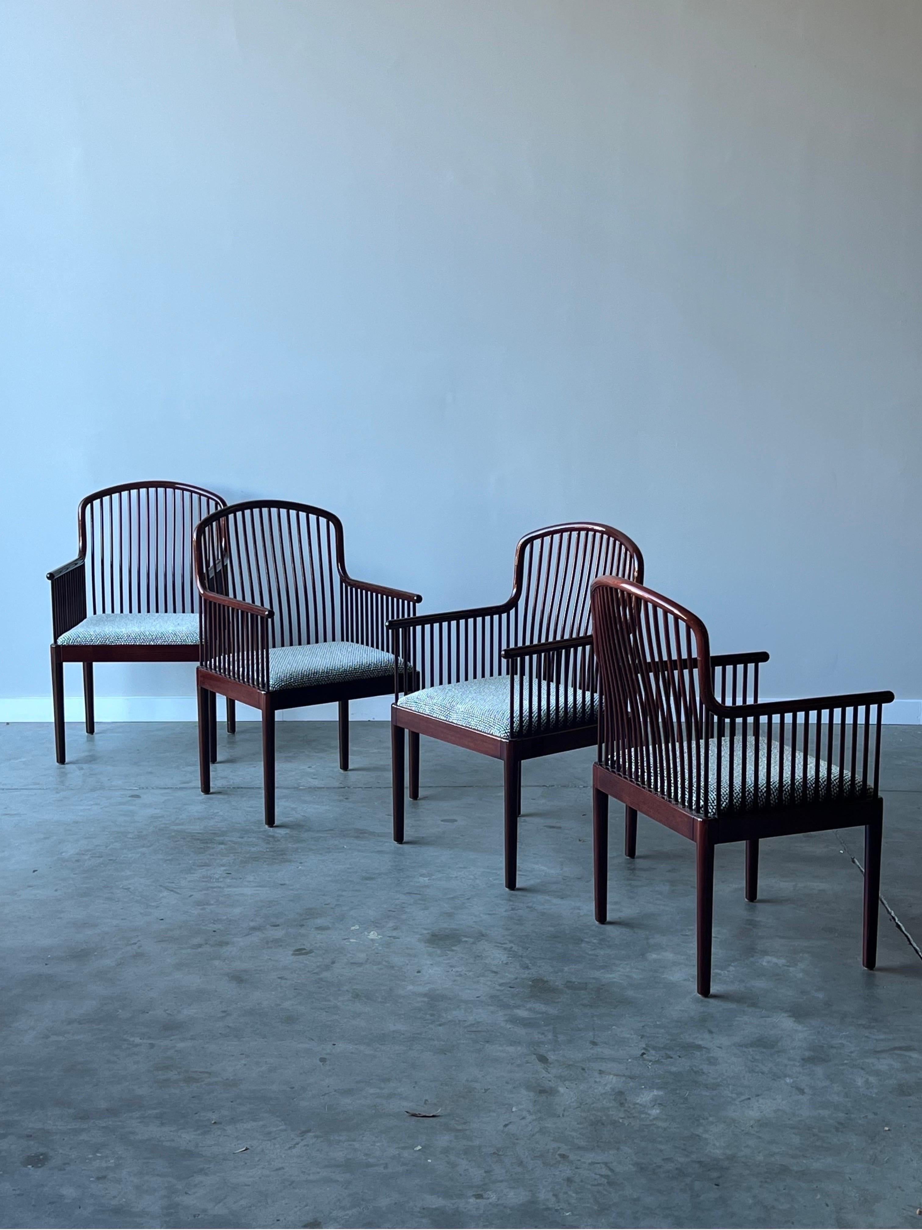 Vintage armchairs designed by Davis Allen for Stendig, circa 1980s. The set of four armchairs are made from rosewood with a glossy finish. Spindles wrap along the arms and backs of the chairs adding depth and dimension to the chairs. Quite a