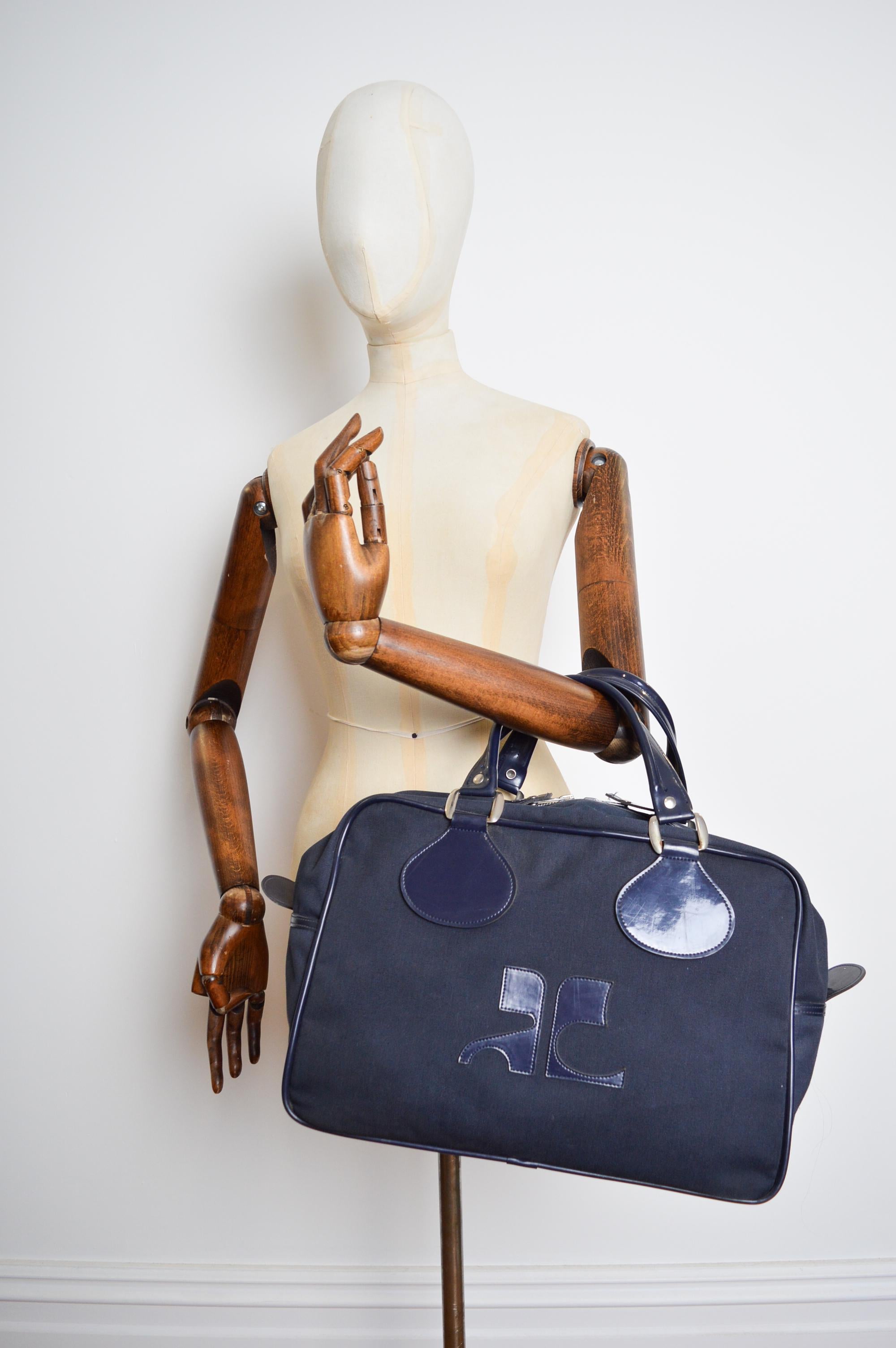 A Chic, Navy Blue Vintage Courréges Holdall bag circa 1970.  

MADE IN FRANCE.  

Features ; Two top handles,  Full Cloth exterior with Large Vinyl Logo and Vinyl lined interior, Single spacious compartment and 4 Metal studs along the bottom for