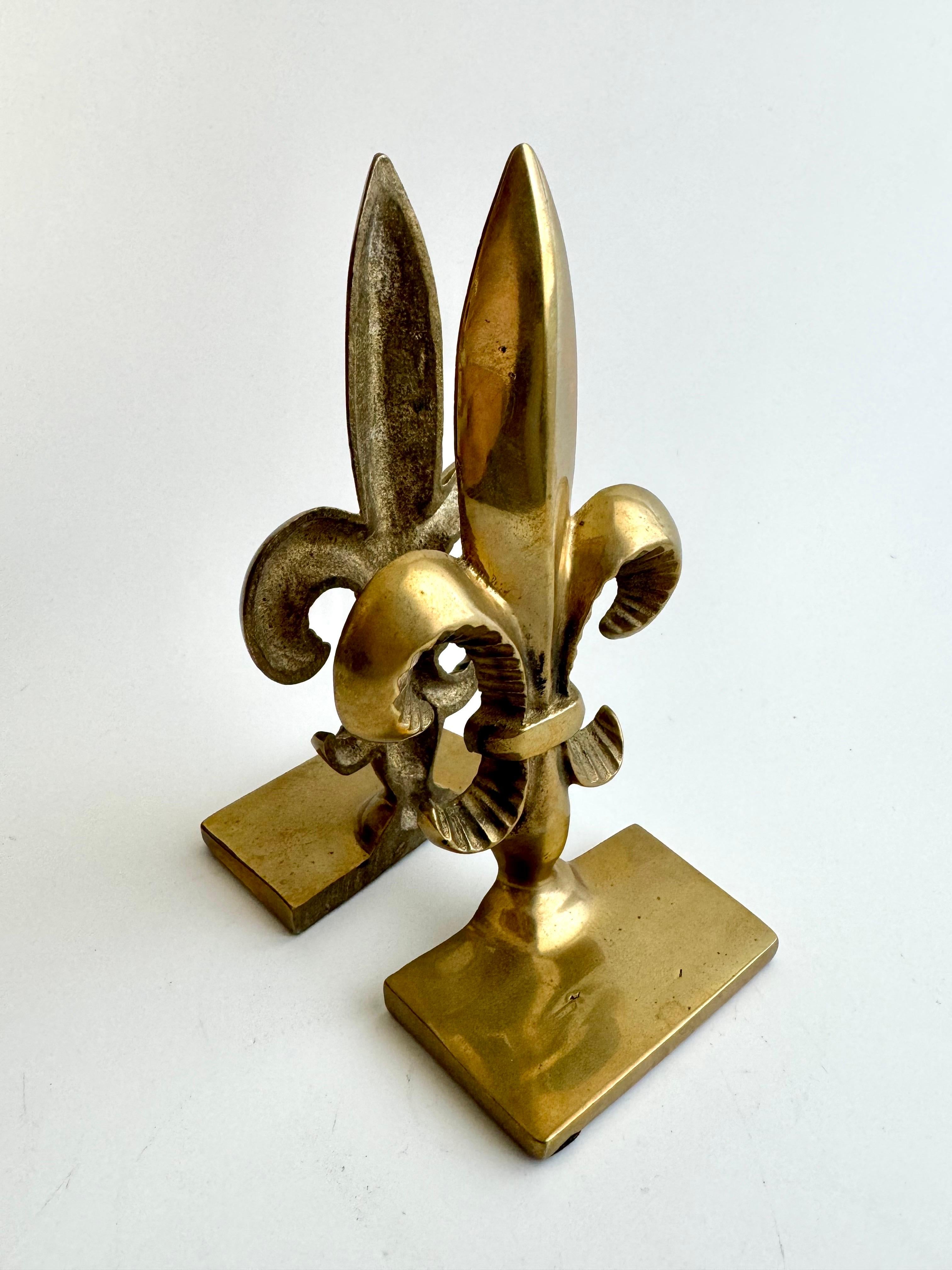 Embrace the timeless elegance of these Vintage Solid Brass Fleur-de-Lis Bookends by Andrea by Sadek. Crafted with precision, each bookend boasts the iconic symbol of nobility and sophistication. Perfect for gracing your bookshelf, mantel, or any