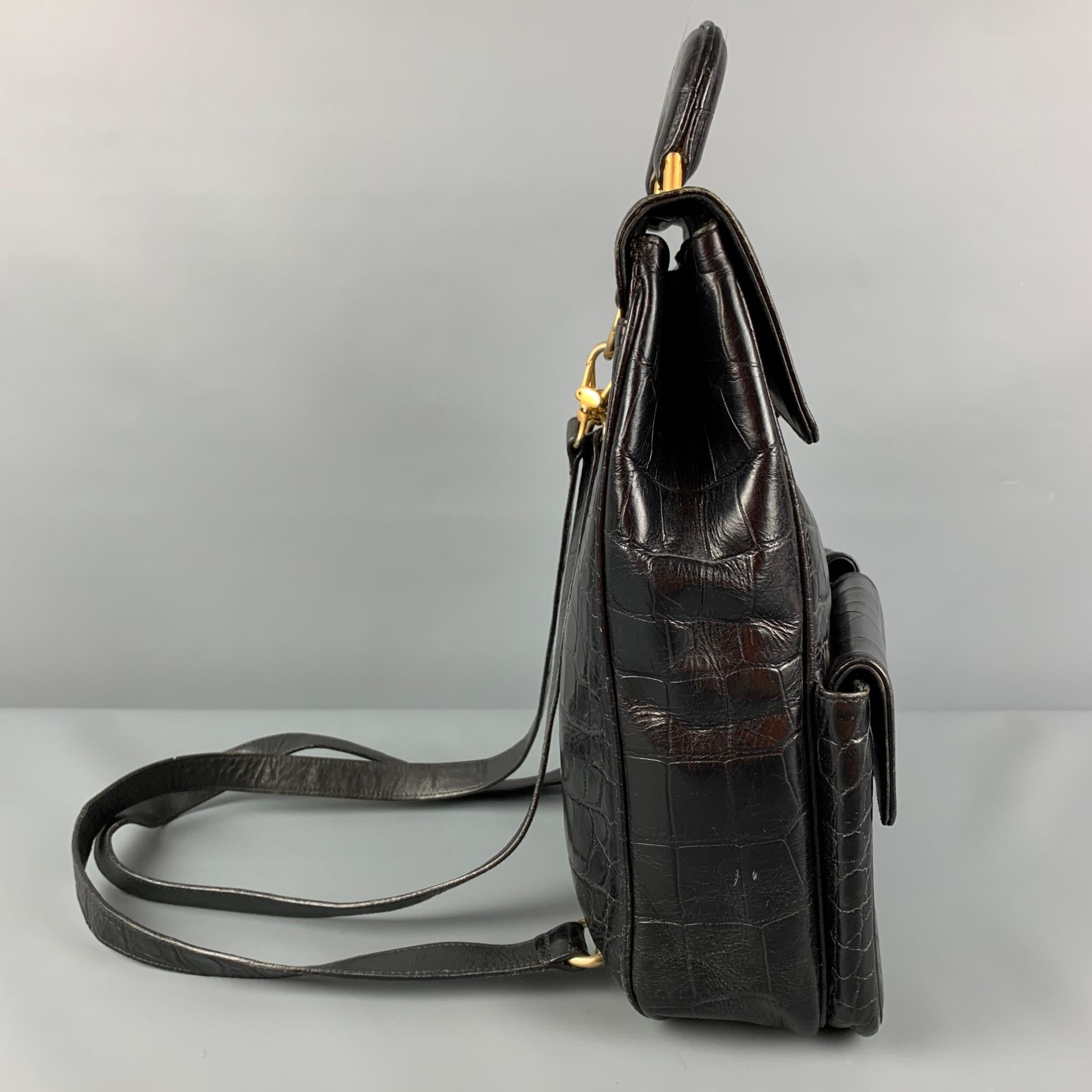 Vintage ANDREA PFISTER backpack comes in a black alligator leather featuring front pockets, top handle, detachable straps, gold tone hardware, inner pocket, and a snap button closure. Made in Italy. 

Good Pre-Owned Condition. Light wear.