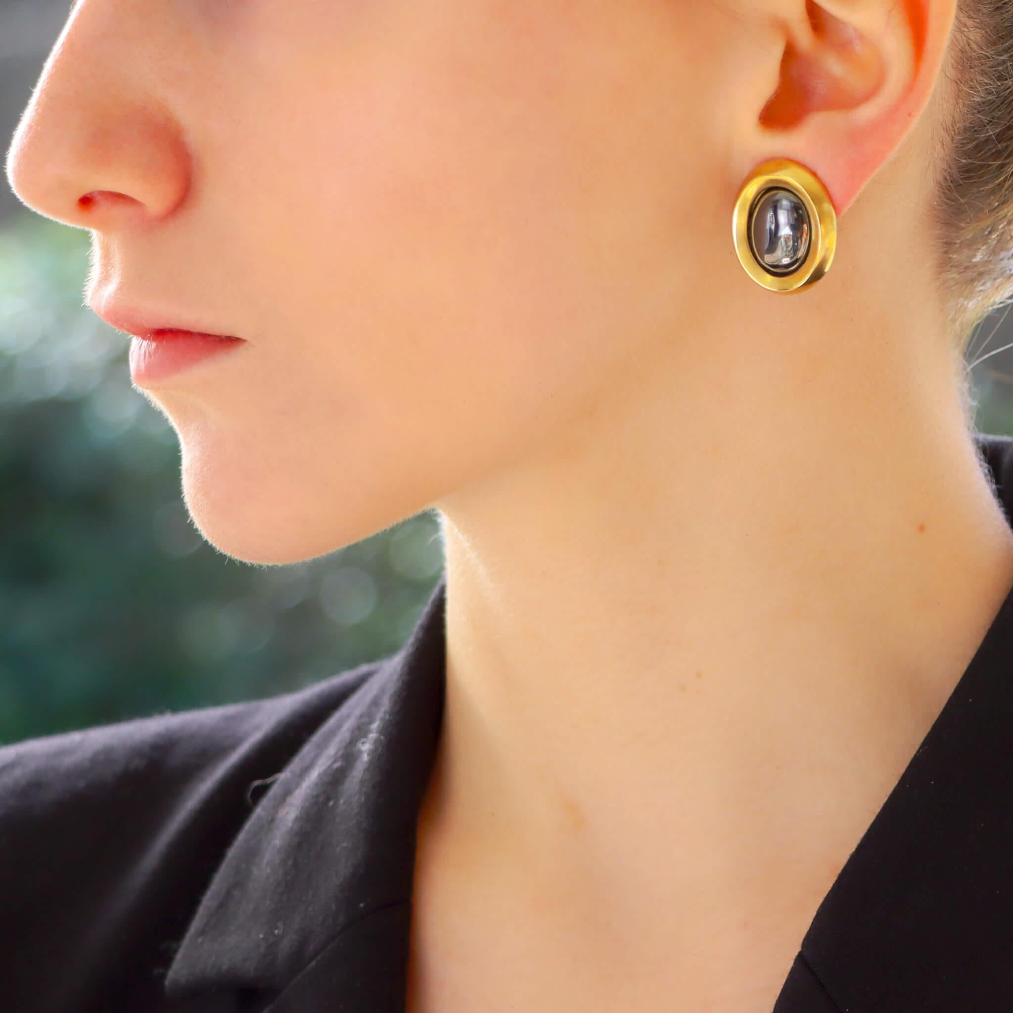 A beautiful vintage pair of Angela Cummings retro inspired earrings set in 18k yellow gold and hematite.

Each earring is centrally set with a metallic lustrous piece of hematite. The hematite is encased in a ‘frame’ of brushed yellow gold. The