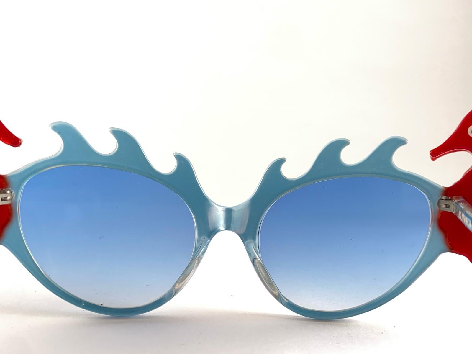 Lunettes de soleil de collection signées par English Anglo American Optical.

New Vintage Anglo American Eyewear Oversized Metallic Blue Frame With Adorned Coral Color Sea Horses Sunglasses With Light Blue Lenses 1970's Made In England.

Cet article