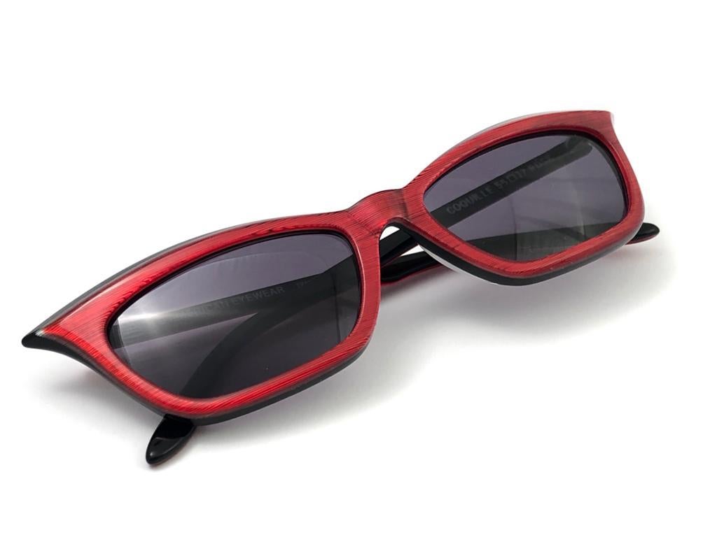 Sleek black and red cat eye style sunglasses signed by English Anglo American Optical.  
Spotless pair of dark grey lenses. 
Made in England.

This pair has minor sign of wear consistent with age and storage.

FRONT  13.5 CMS
LENS HEIGHT 3 CMS
LENS