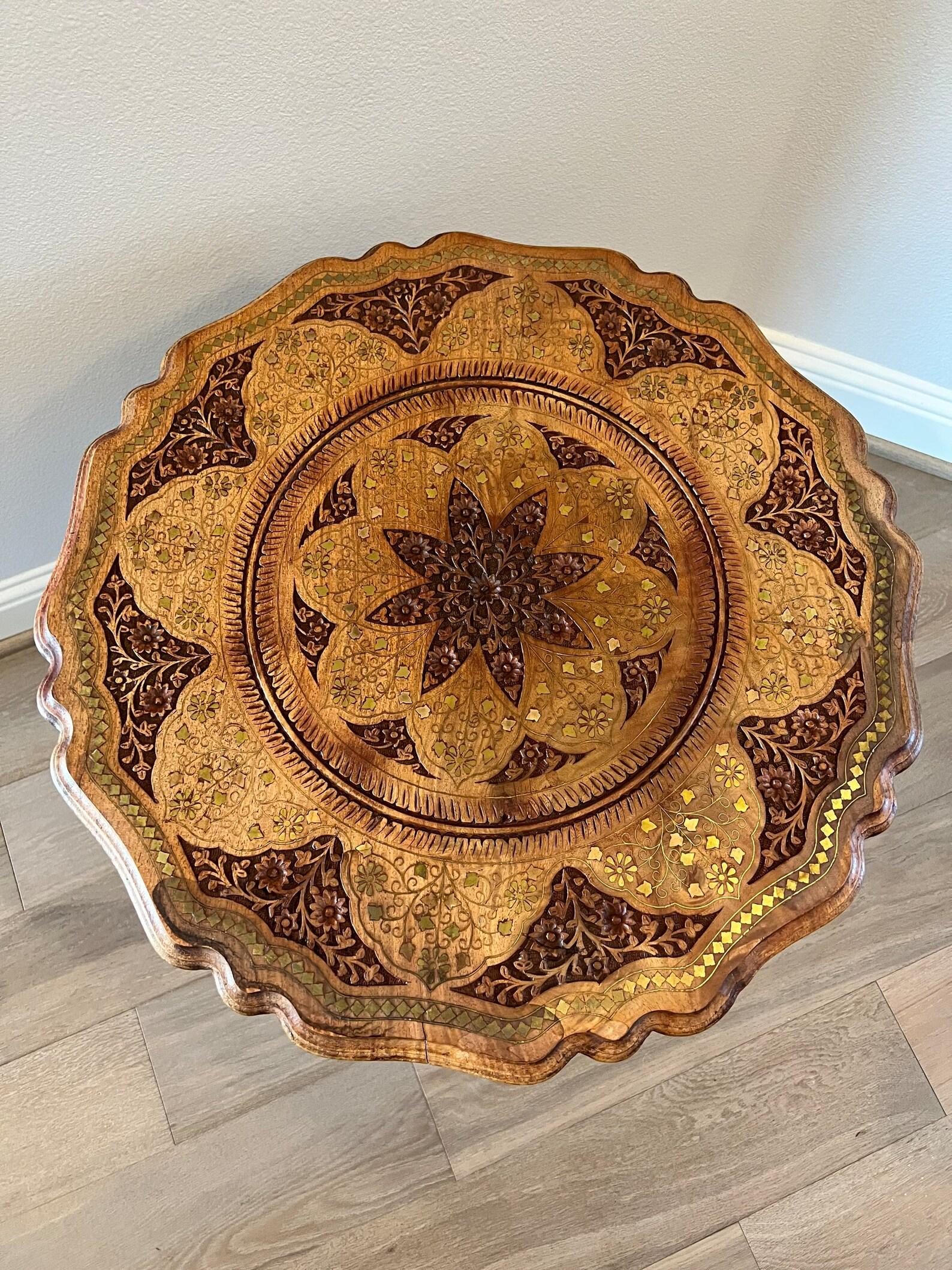 A vintage Anglo-Indian hand-carved solid wood round tripod pedestal end table with stunning brass inlay throughout. 

Hand-crafted in India in the second half of the 20th century, featuring a circular top with stepped scalloped edge framing