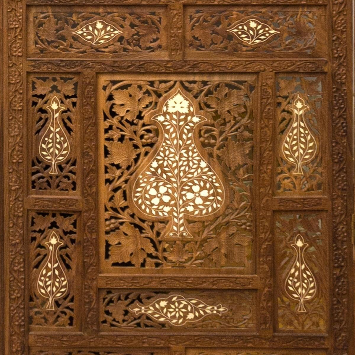 A vintage, hand-carved wood screen in the Anglo Indian style with four panels; one side features an inlay design and the other side has brass decorative accents. 

Screen includes two additional panels for a total of six possible panels. 

Each of