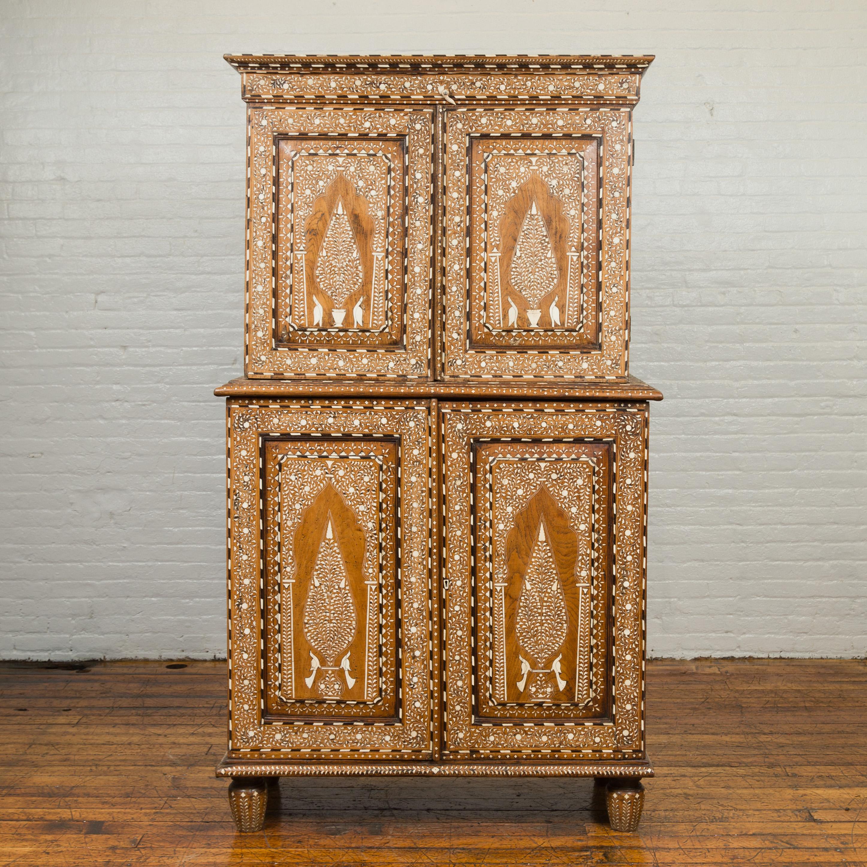 A vintage Anglo-Indian sheesham wood wardrobe cabinet from the first half of the 20th century, with birds flanking a tree, ebonized accents and bone inlay. Born in India during the 1940s, this two-section cabinet is adorned with an abundant décor of