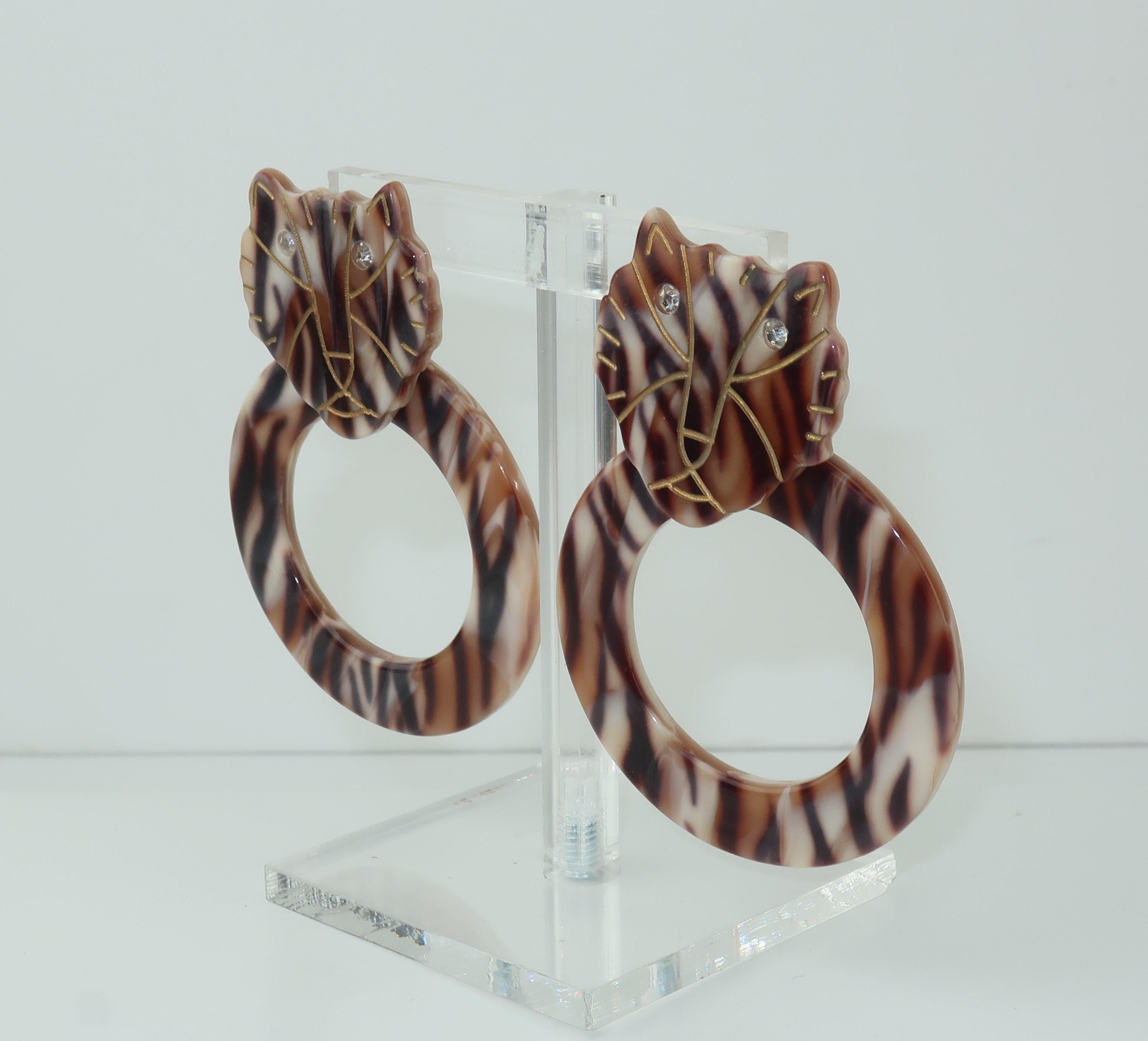 Walk on the wild side with these adorable tiger print door knocker earrings fabricated from layered acrylic in shades ranging from ivory to dark brown. The tiger's expressive face is achieved with dark gold etched lines and crystal rhinestone eyes.