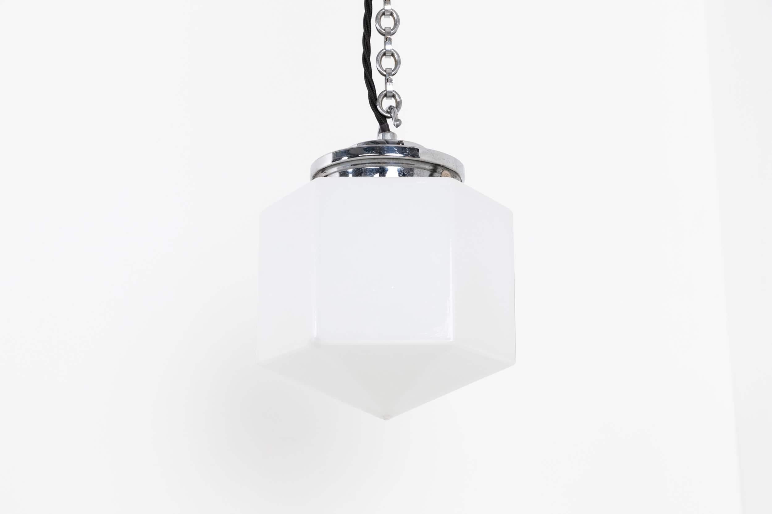 

A diminutive art deco hexagonal opaline pendant lamp. c.1930.

Thick pressed white opaline glass light shade with its original nickel plated stepped gallery, chain and ceiling hook. The look fantastic in a porch with your door number/named painted