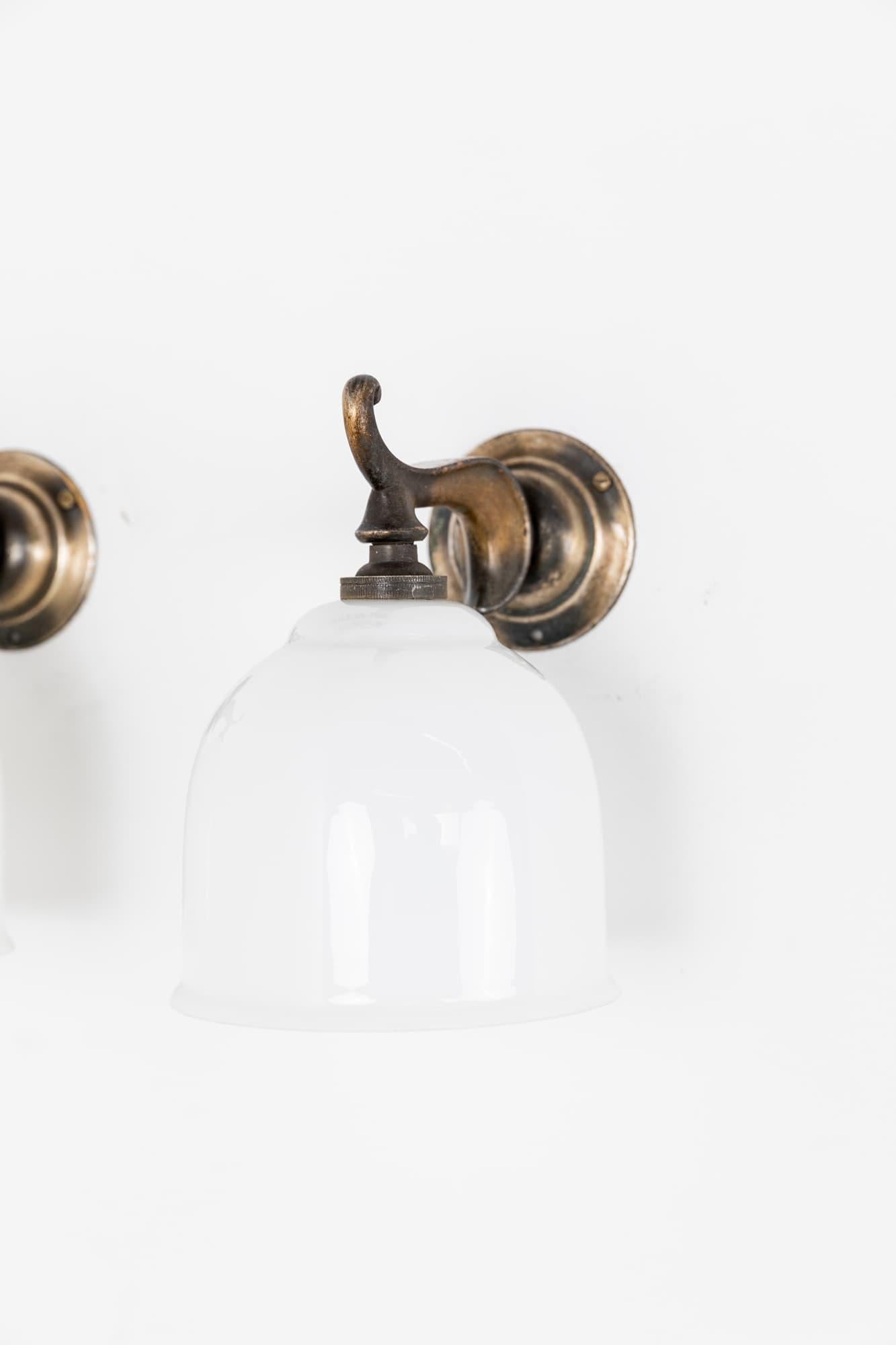 An incredibly elegant pair of wall mounted lamps made in England by GEC. c.1920

The simply formed diminutive silver-plated brass mounts with opaline glass shades. Priced as a pair.
