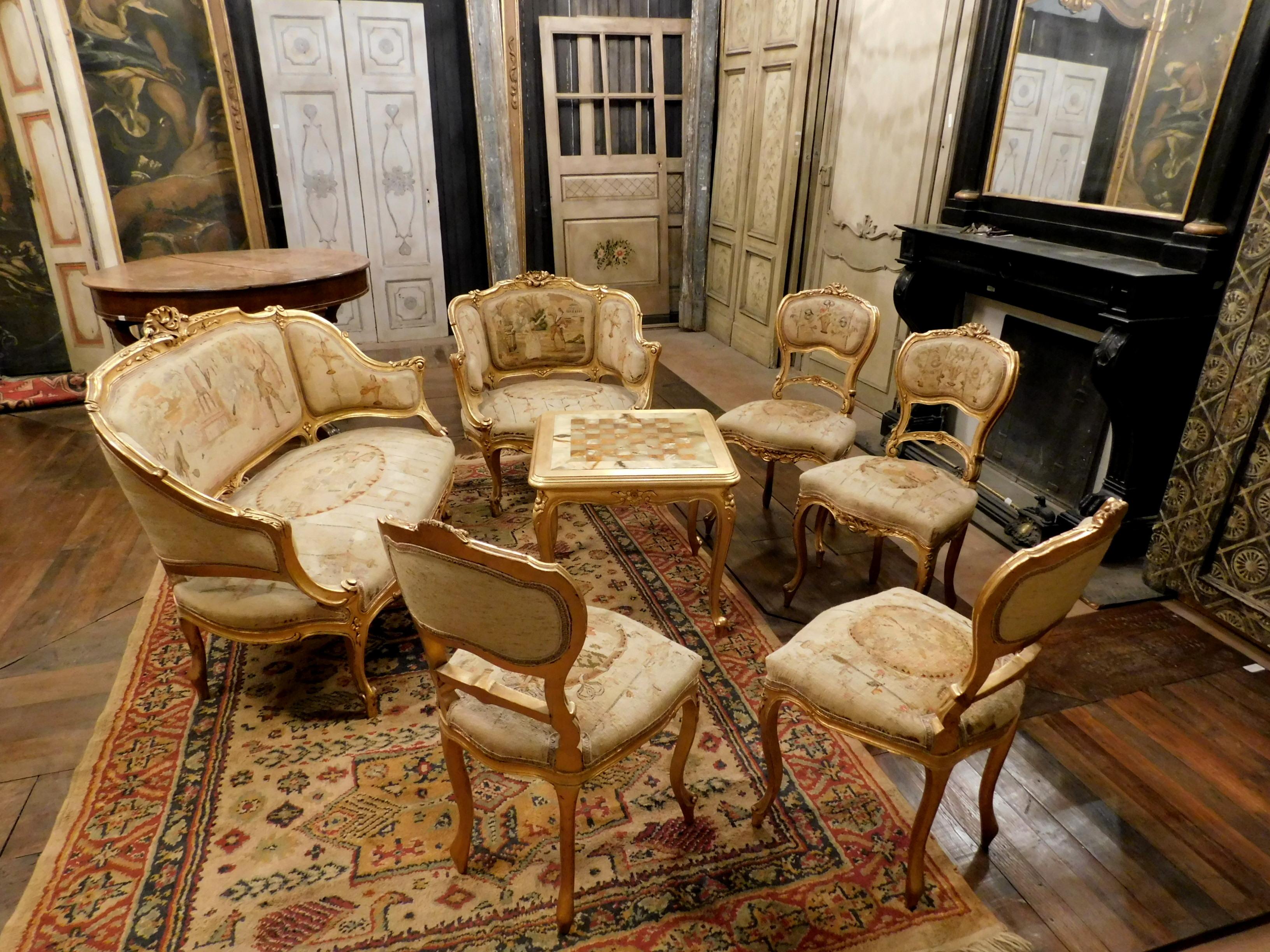 Vintage antique golden living room complete, hand built in the late 19th century in Italy, consisting of a sofa, an armchair, 4 chairs and a coffee table, gilded sculpted structure with upholstery in excellent condition depicting worldly scenes