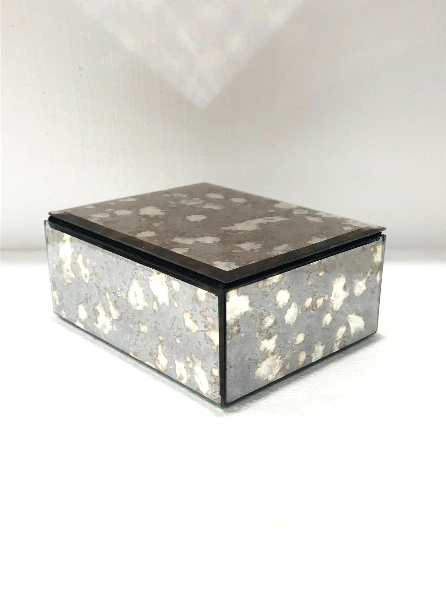 Vintage Hollywood Regency decorative box. The mirrored box captures the beautiful gradient movement of agate stone with antique spotted glass in hues of grey and bronze. The box features beveled edges with a hinged lid and a black felt interior and