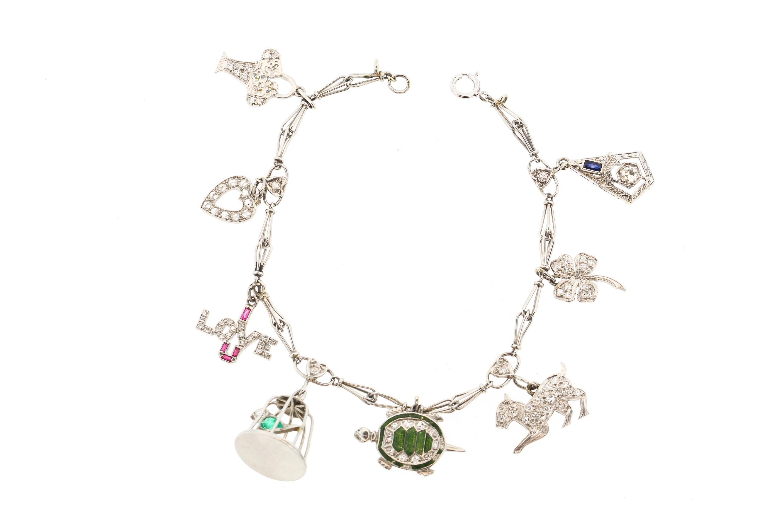 Antique platinum and gems charm bracelet circa 1935. The charms are of matching scale and make to create a lovely filled charm bracelet. The charms are a basket, a heart, an I LOVE U charm, a bird in a cage, a turtle, a dog, a clover and a small
