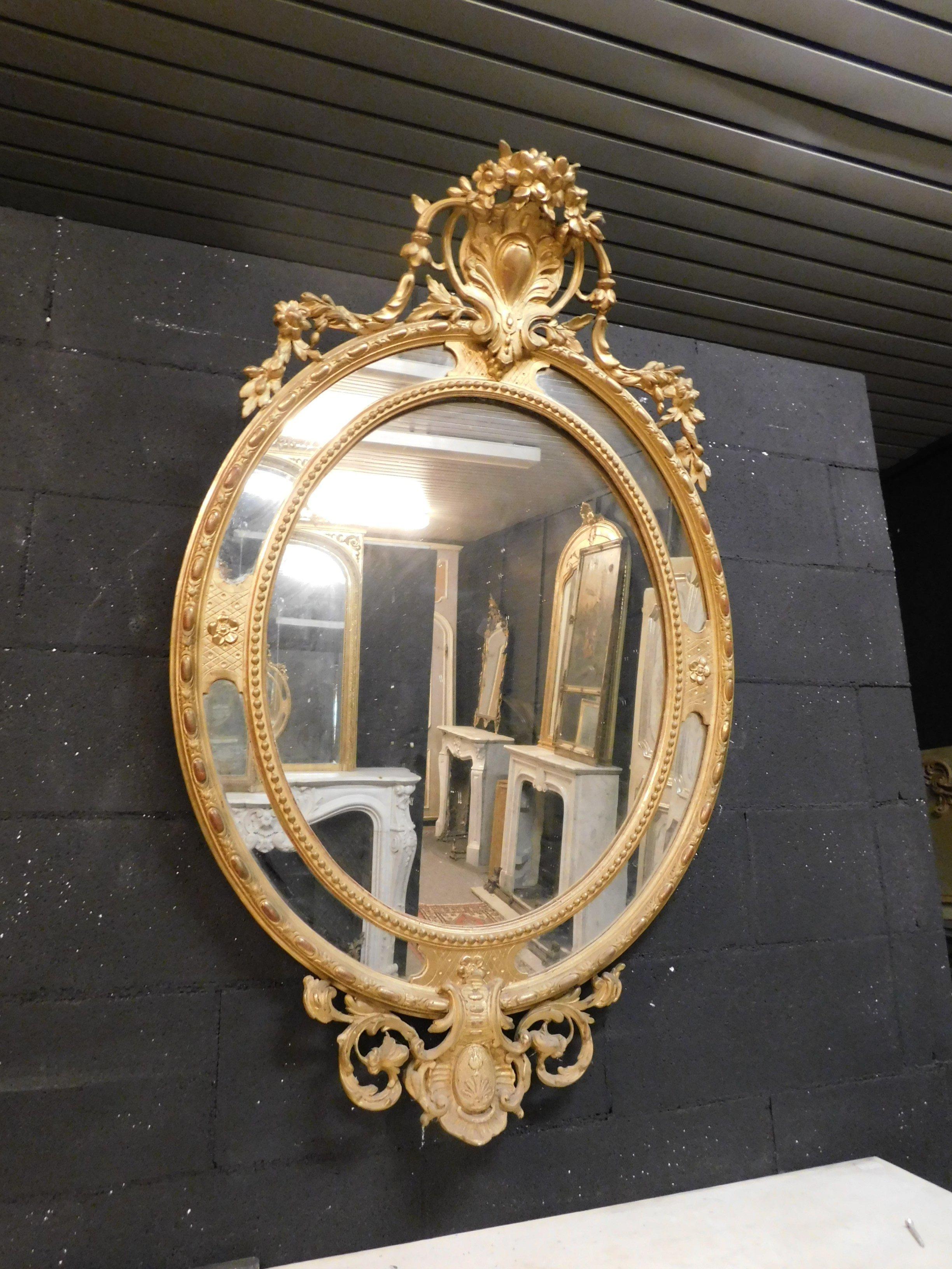 Vintage antique oval mirror, richly carved in wood and gilded, very flashy and beautiful, ideal to hang on the wall, above a fireplace, a sideboard or an entrance to give light and space (even in a luxury bathroom). Built in the 19th century in