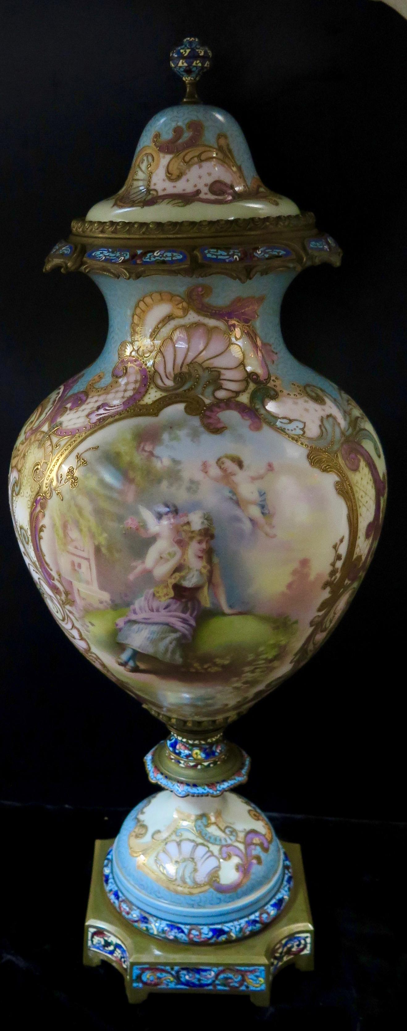 This vintage antique hand painted porcelain palace size urn dates from the late 19th century. The baluster shape urn & lid are elaborately decorated with a scrolling motif highlighting a detailed scene of a young maiden in a garden with attending