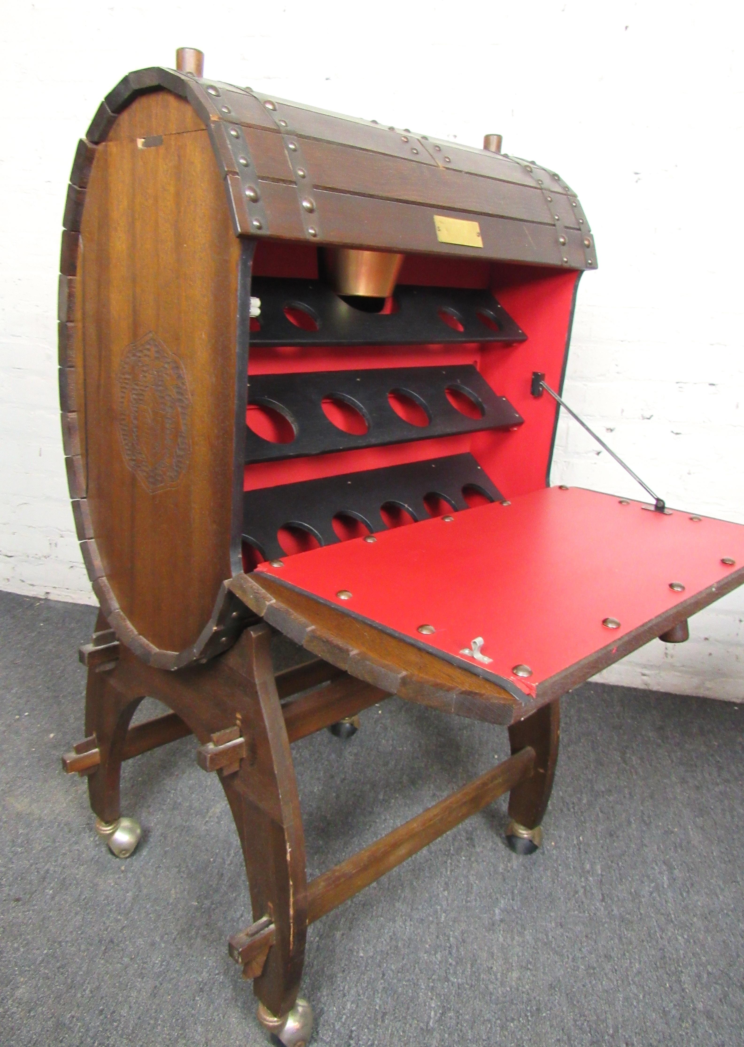 Antique style wood rolling bar. Contains two side leaves that fold down to reveal bar with storage for small and large bottles/glassware, as well as an ice bucket on top. Rich wood grain and solid metal details complete this classic barrel style