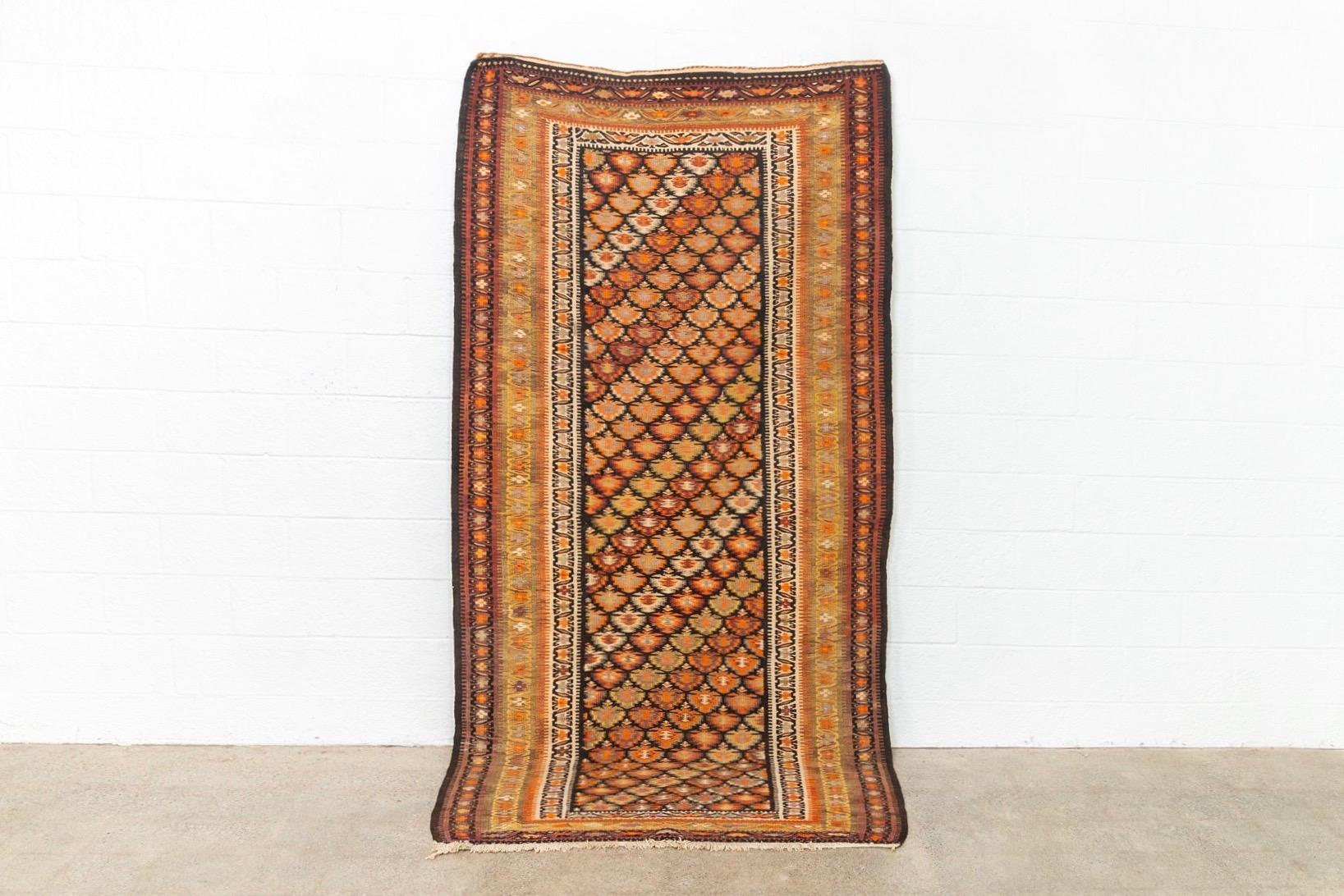 This elegant antique Veramin Kilim floor rug circa early to mid 1900s is expertly hand knotted from all-natural, vegetable-dyed wool and displays traditional Veramin style and tribal motifs. The intricate design is comprised of a symmetrical central