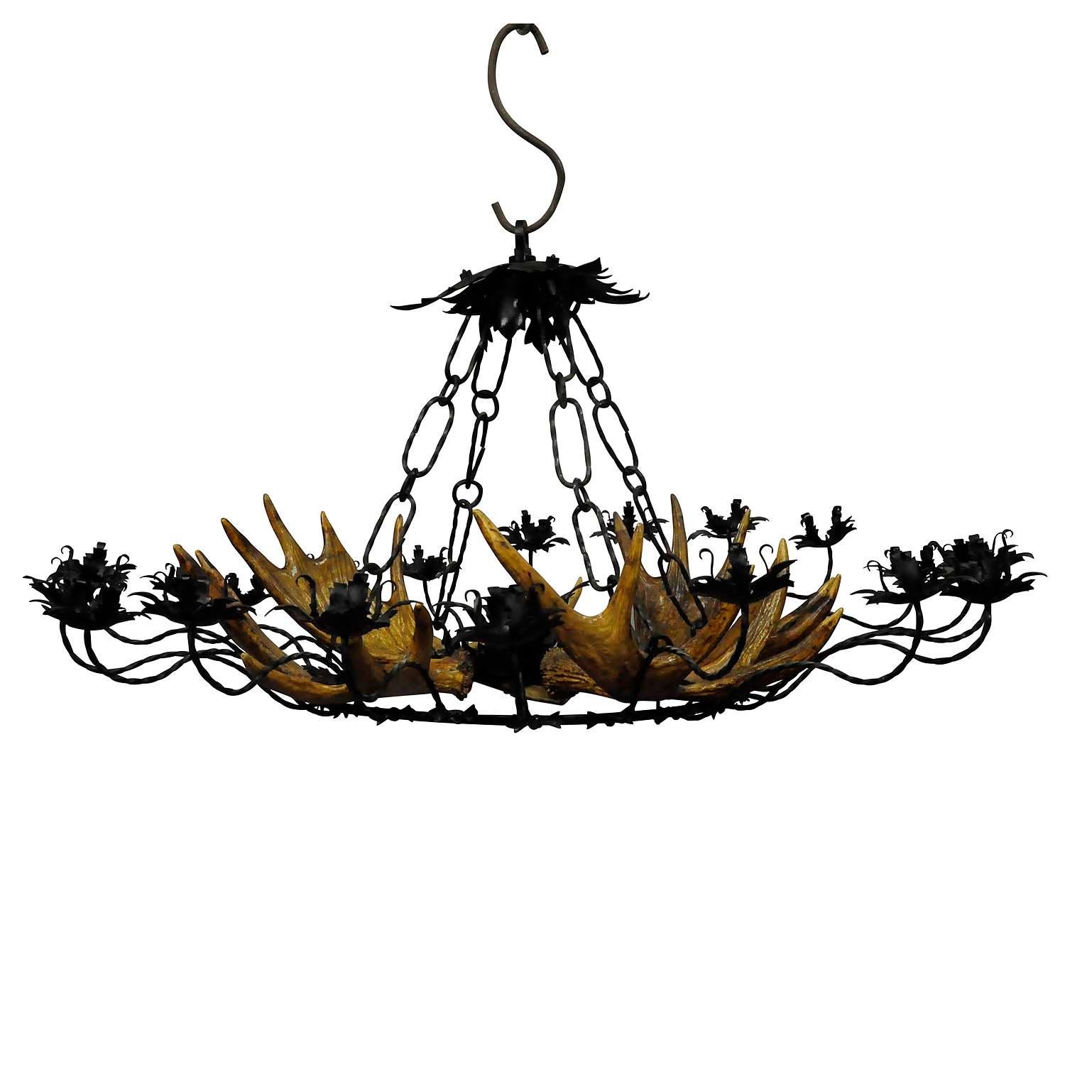 Vintage Antler Chandelier with Forged Iron Suspension

A beautiful filigree forged iron chandelier with 4 large elk antlers. Manufactured in Germany ca. 1950s. The chandelier features 20 spouts for candles and is not electrified. The suspension is