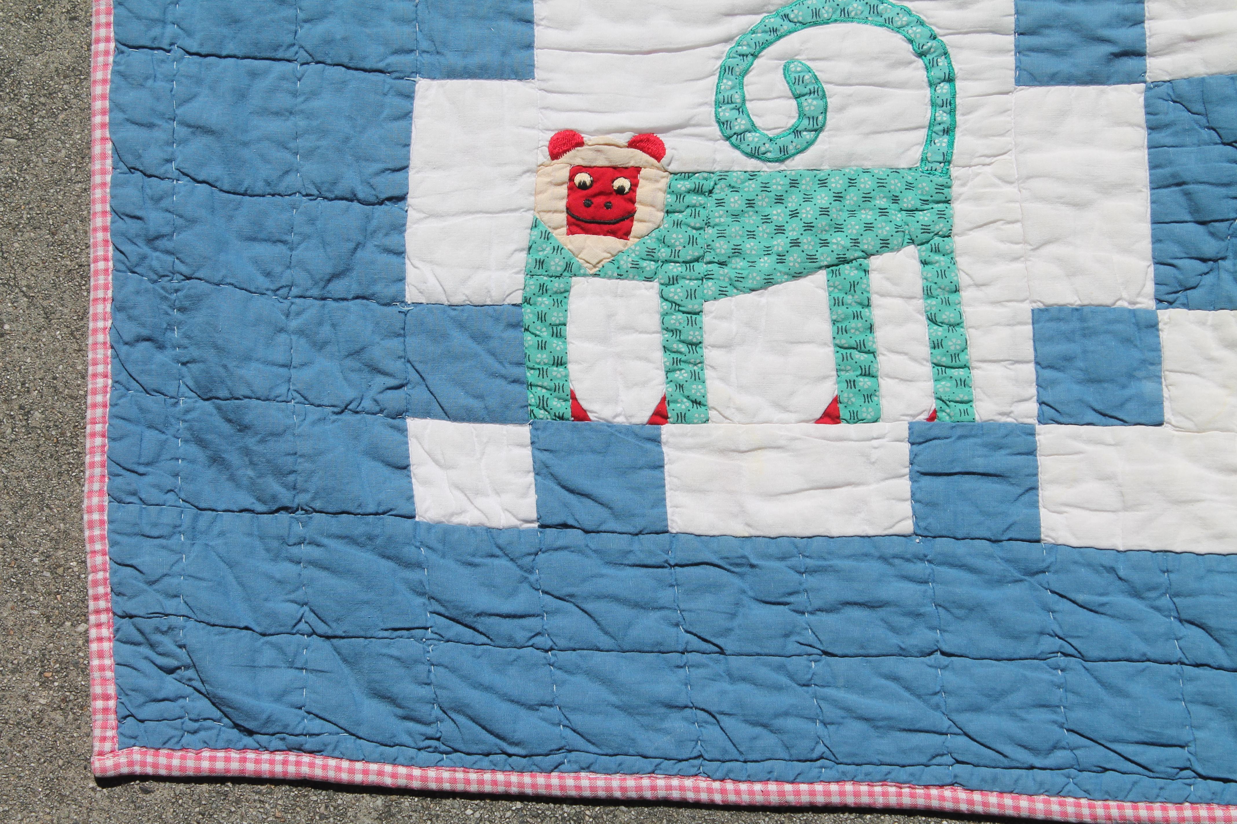 Vintage pictorial crib quilt with applique animals. Blue and white background and red and white check backing.