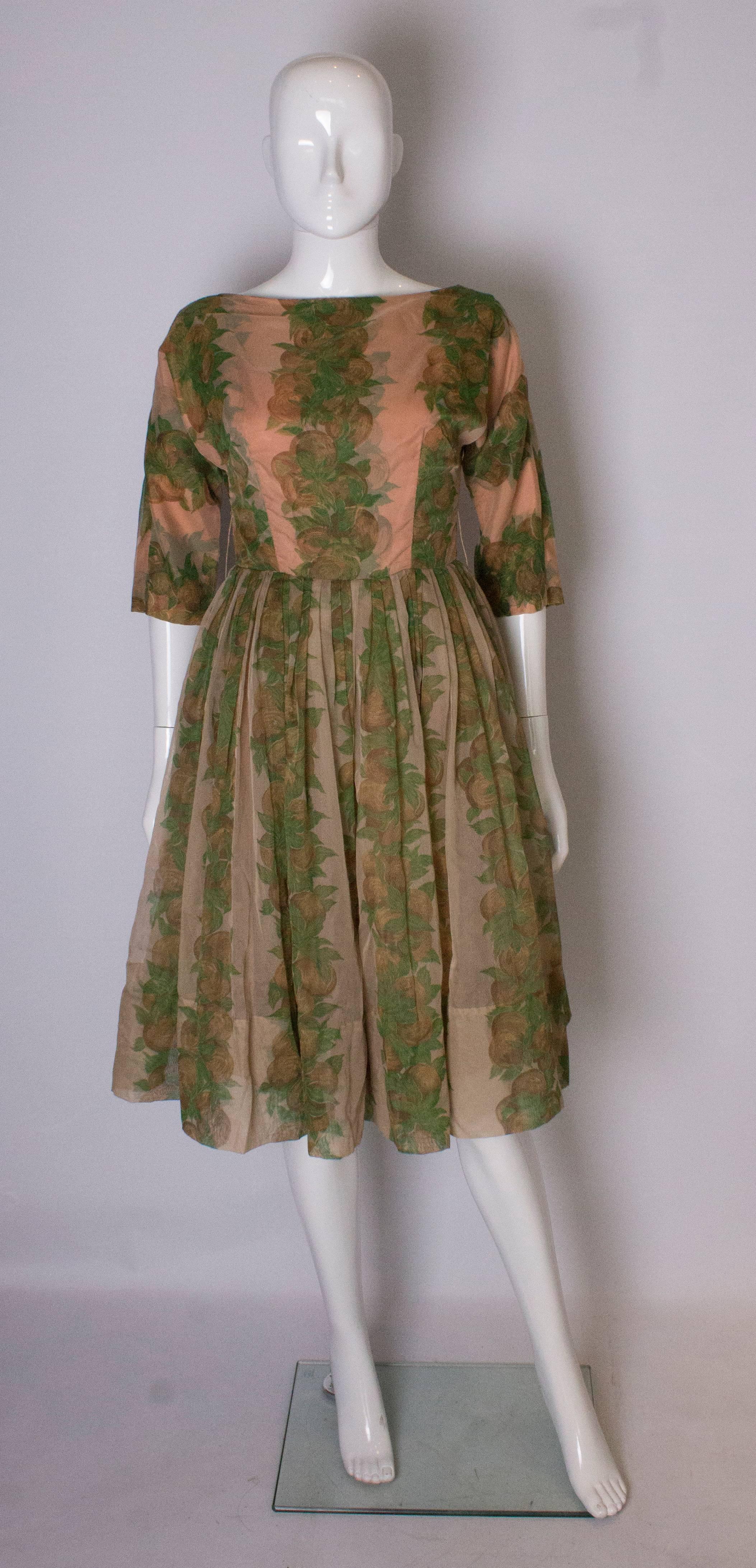 A great  1950s party dress in a wonderful summer print in shades of apricot , green and brown. It has a fabric underskirt in the same print as the top fabric,and there is a net skirt in between. The dress is gathered at the waist, with elbow length