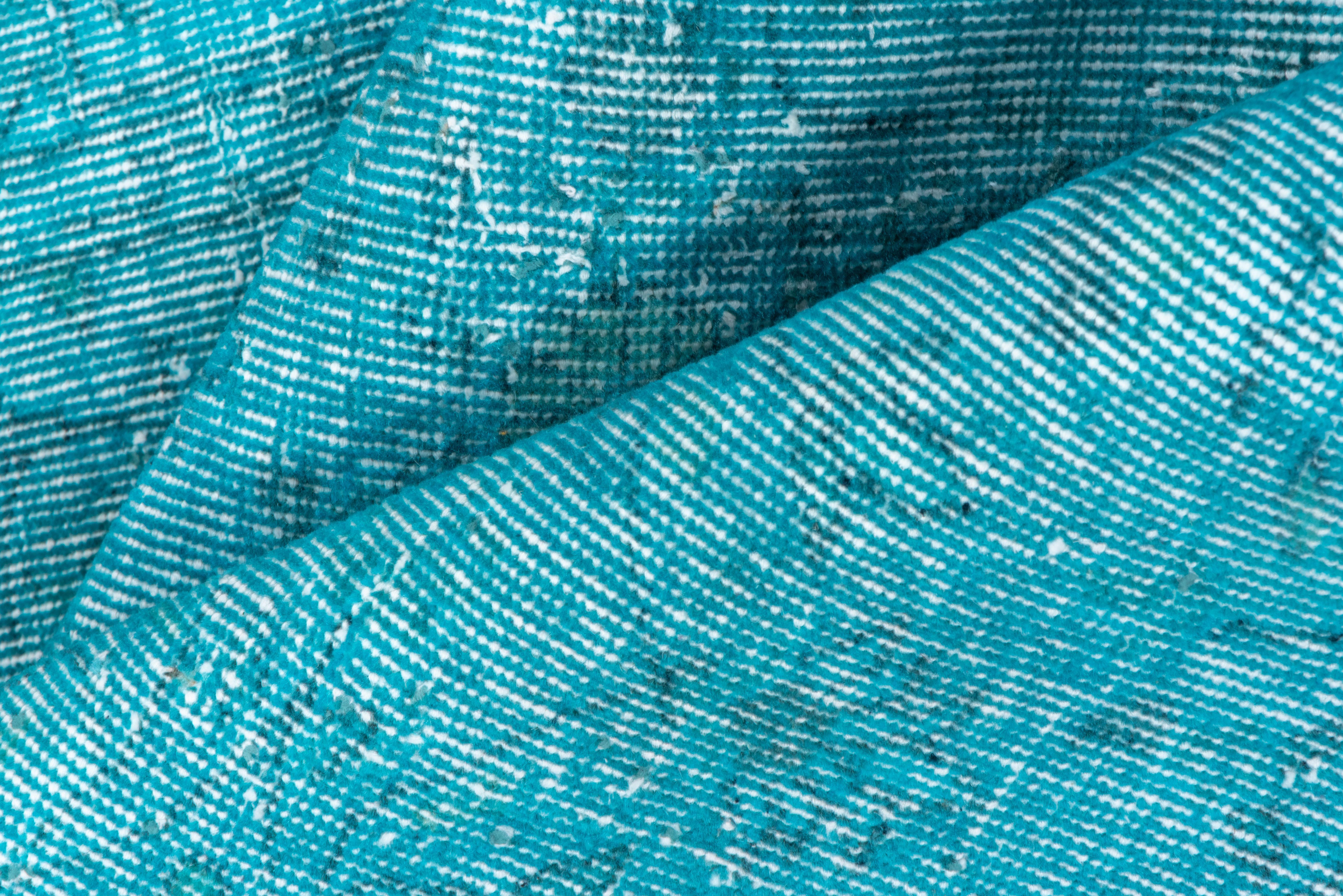 Ce tapis Sparta turc surteint aqua et turquoise présente un motif défini par l'usure au-delà de la détresse générale. Des bandes verticales et horizontales de couleur blanc cassé se croisent près du centre. Les conditions shabby chic et peuvent