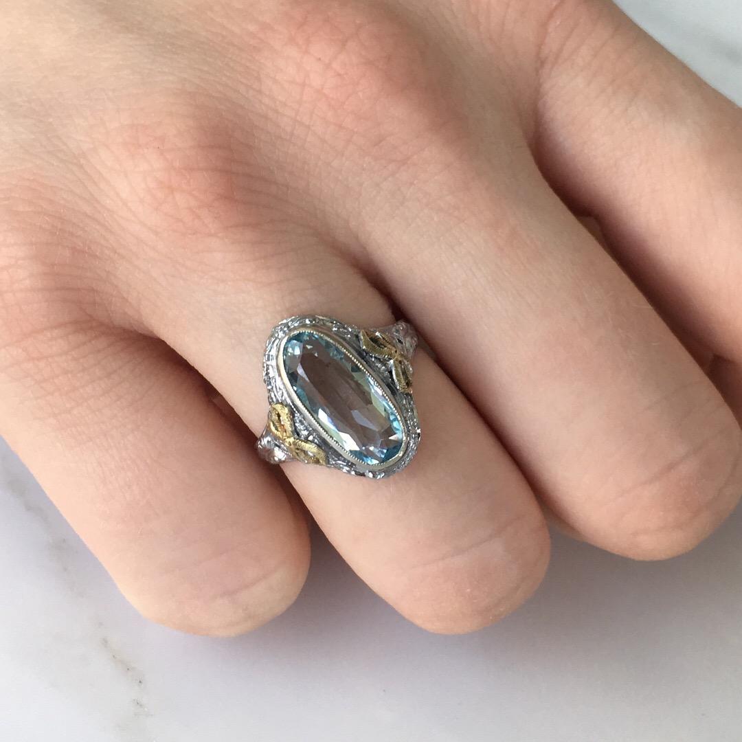 Details:
Stunning 14K white gold filigree, aquamarine ring—with tiny yellow gold ribbons surrounding the setting! The aquamarine measures 13.25mm x 6mm, with a classic beautiful light blue color. The height of the aqua at the center of the setting